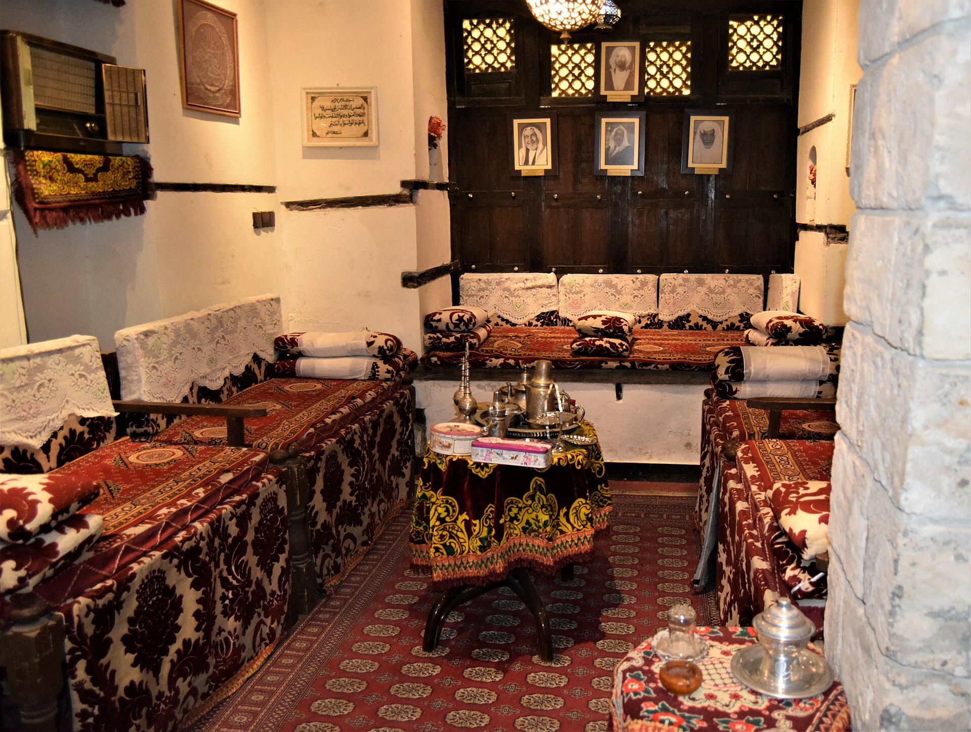 A traditional majlis sitting room in a historic Jeddah house with cushioned seating, ornate carpets and Arabic coffee service