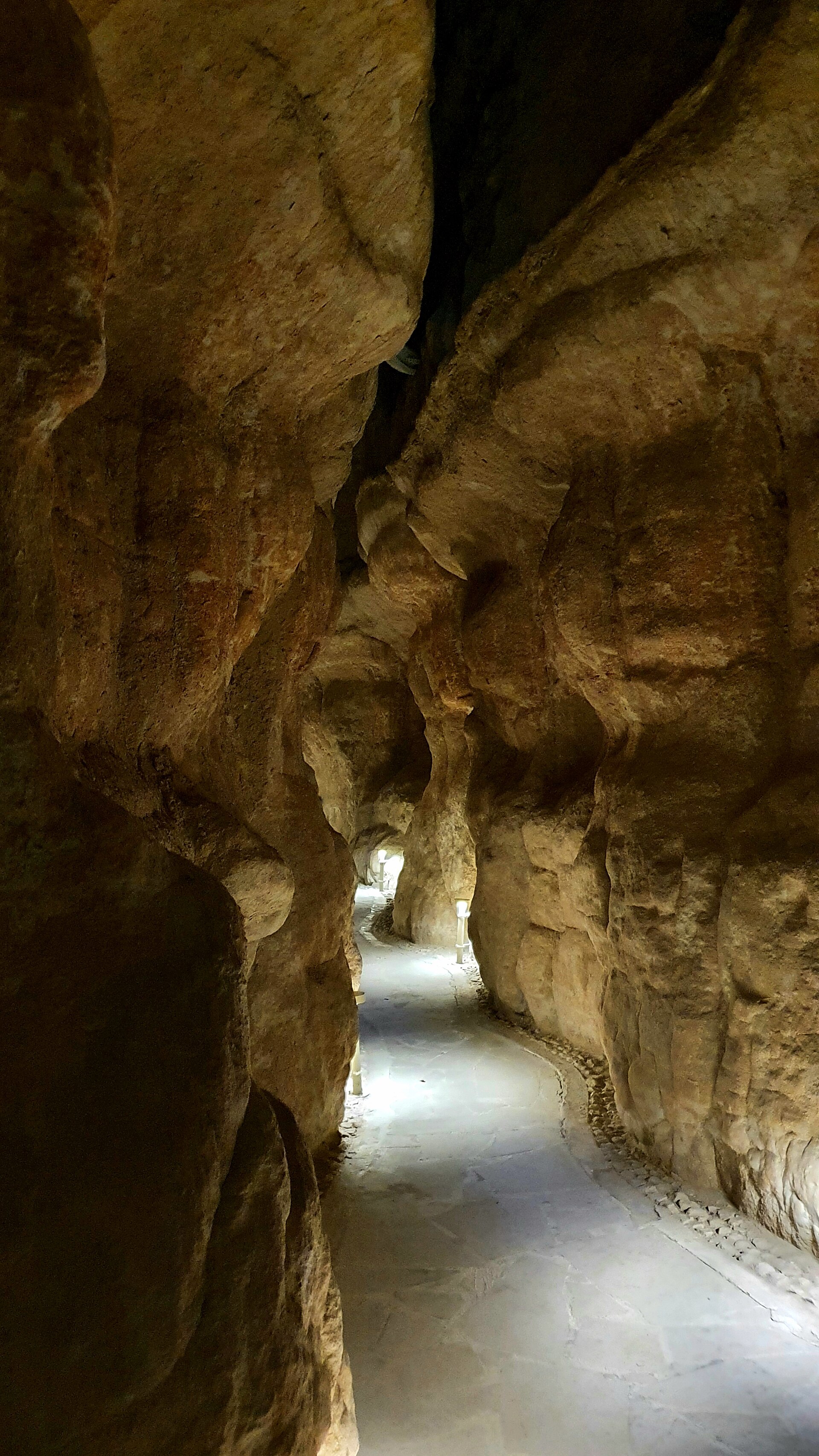 Narrow limestone passage inside Jabal Al-Qarah caves near Al-Ahsa, with light filtering through eroded rock walls