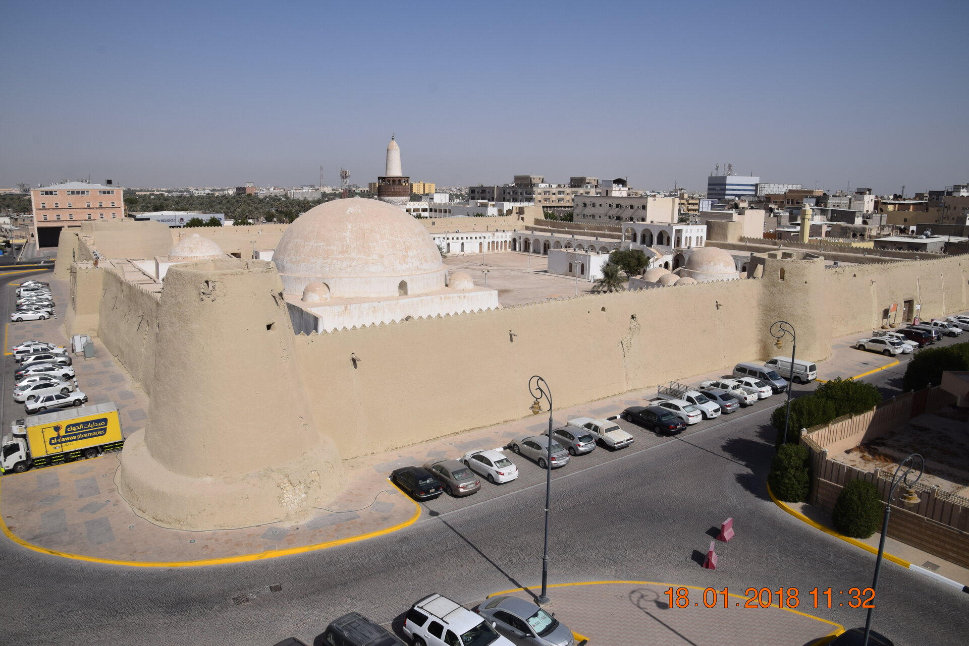 Aerial view of Qasr Ibrahim fortress in Hofuf, showing its domed mosque and crenellated walls surrounded by the modern city