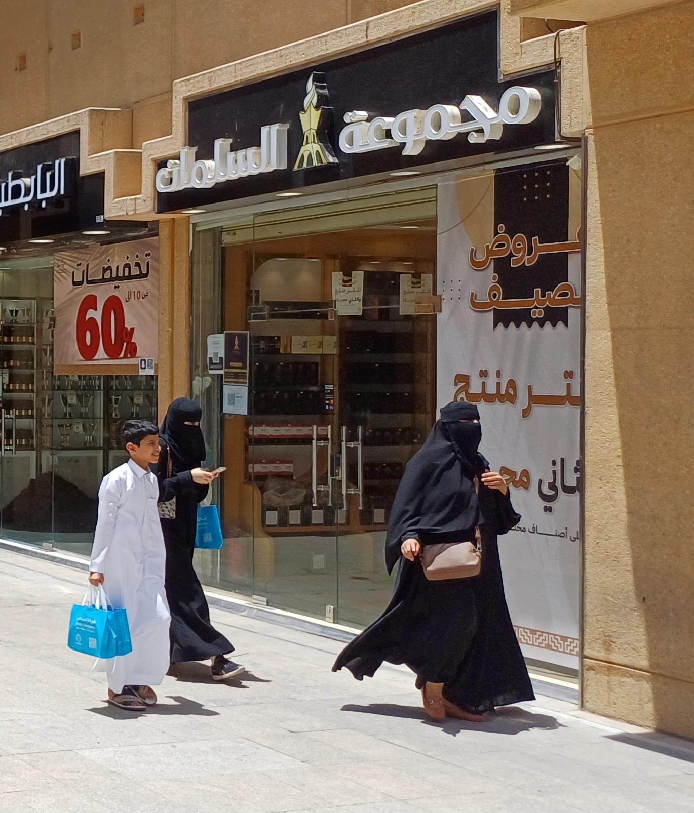Saudi women in traditional black abayas walking through a shopping district in Riyadh