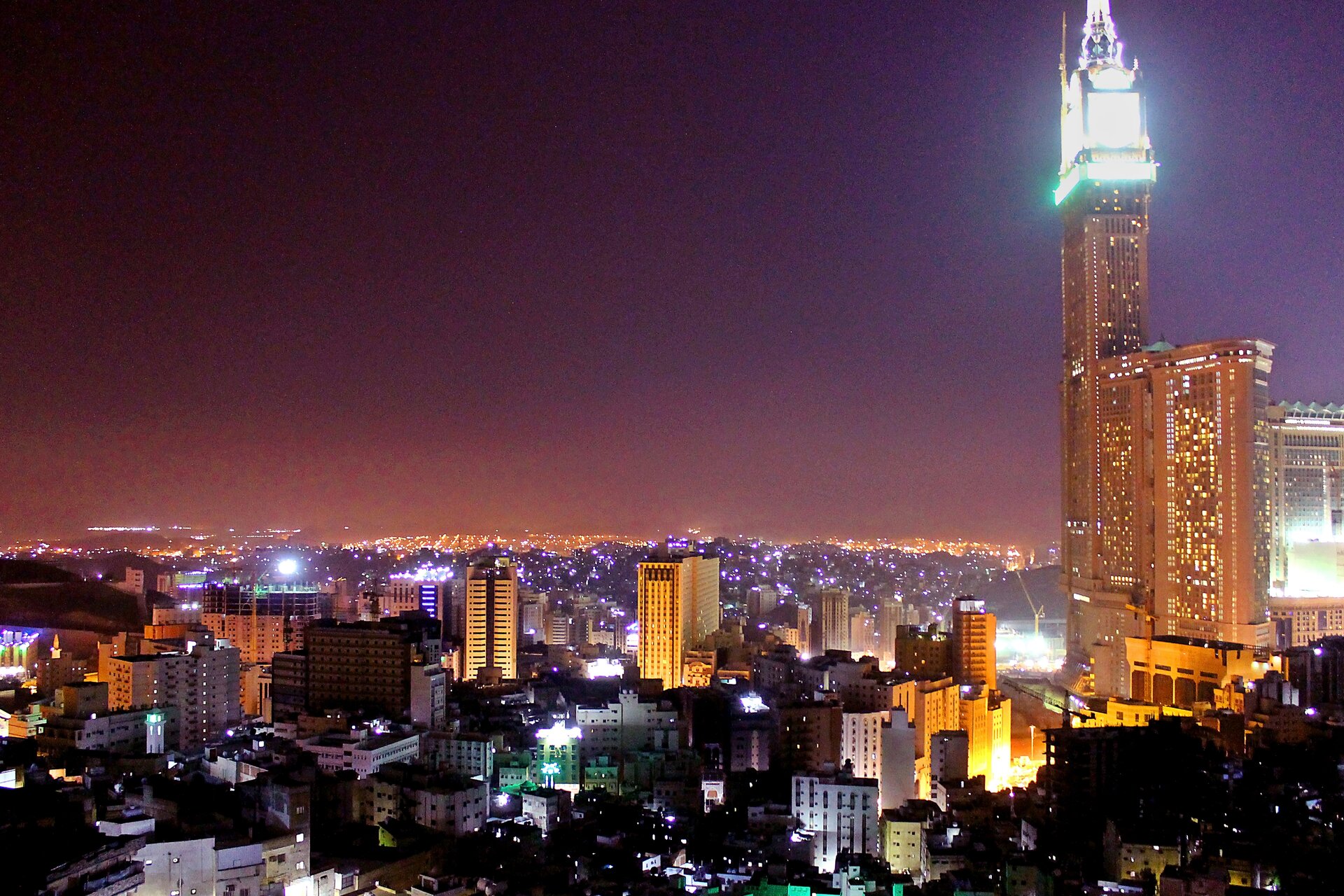 Mecca city skyline at night showing the Abraj Al-Bait Clock Tower and surrounding hotel towers for pilgrims