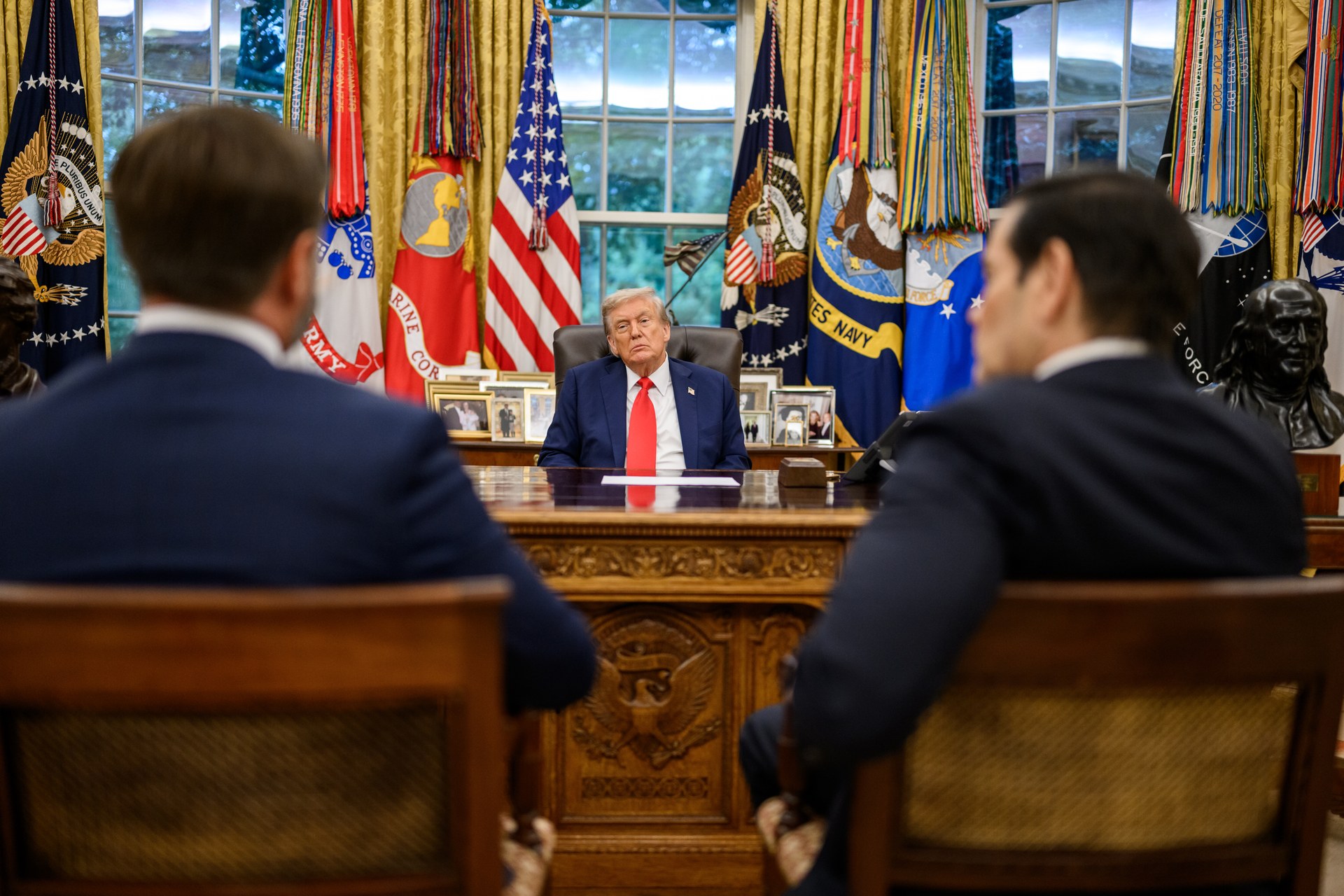 President Trump seated at the Resolute Desk in the Oval Office with Vice President JD Vance and Secretary of State Marco Rubio, the national security team directing simultaneous threats and diplomacy toward Iran in April 2026