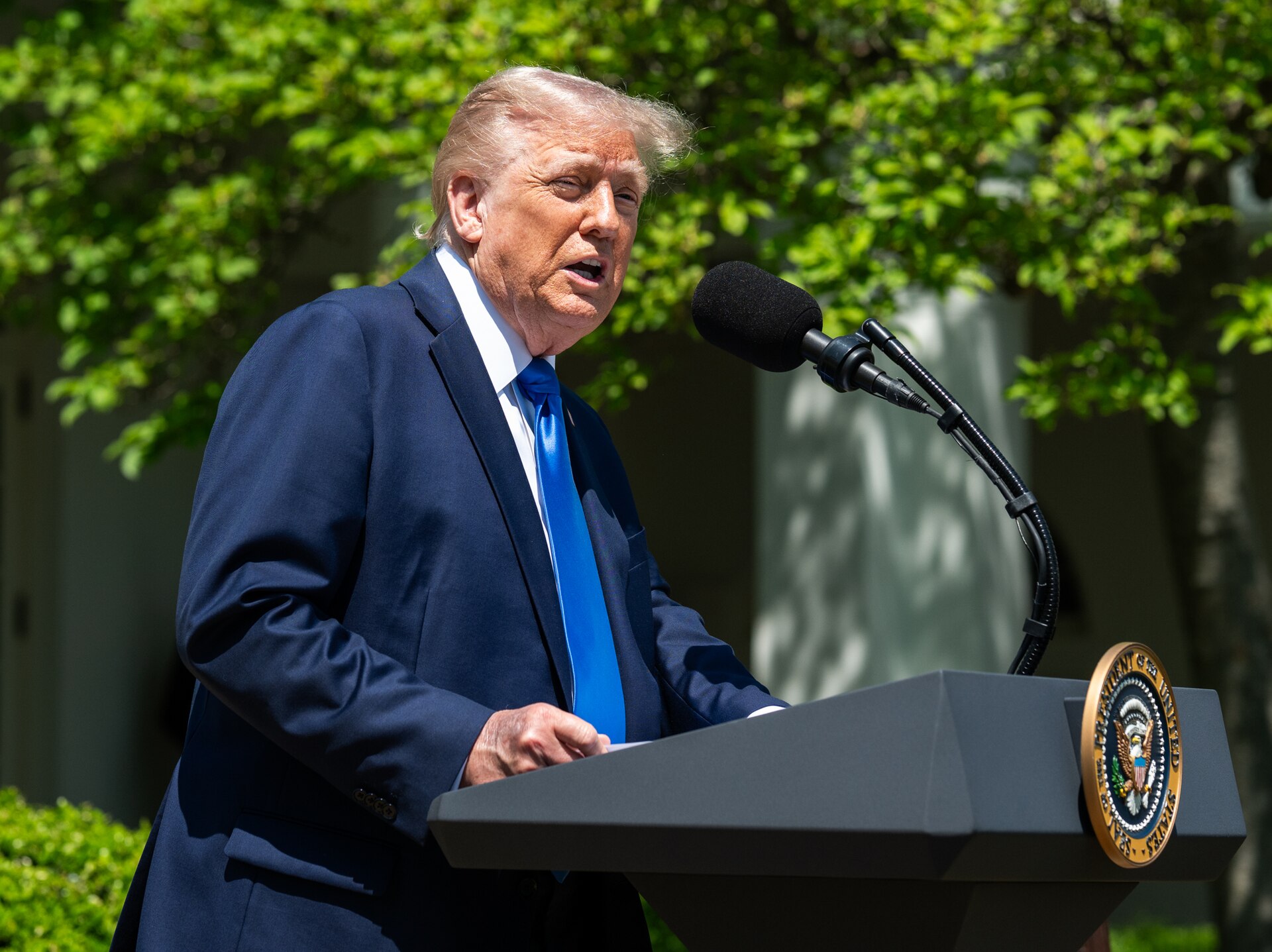 President Trump speaking at White House podium with presidential seal, May 2025