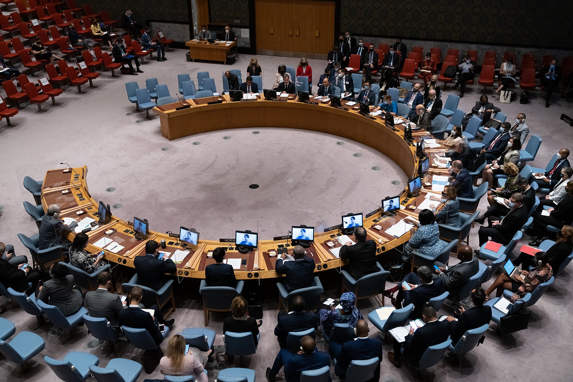 UN Security Council in full session with delegates seated at horseshoe table during a vote or deliberation, New York