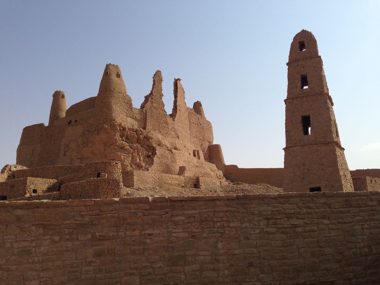 Marid Castle and the minaret of the Omar ibn al-Khattab Mosque in Dumat al-Jandal, seen from ground level at sunset