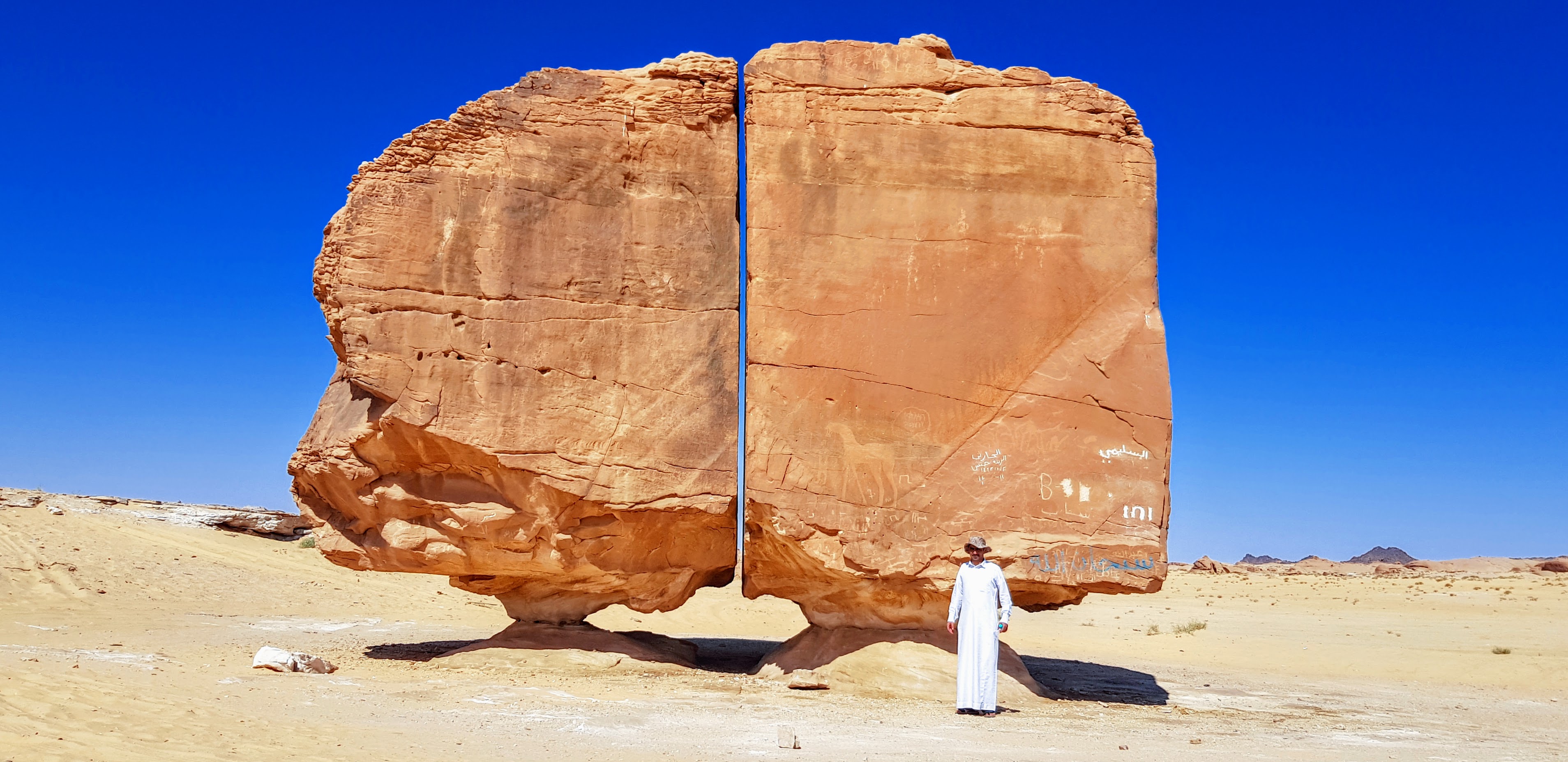 Al Naslaa split rock formation near Tayma, Saudi Arabia, with ancient petroglyphs visible on the surface