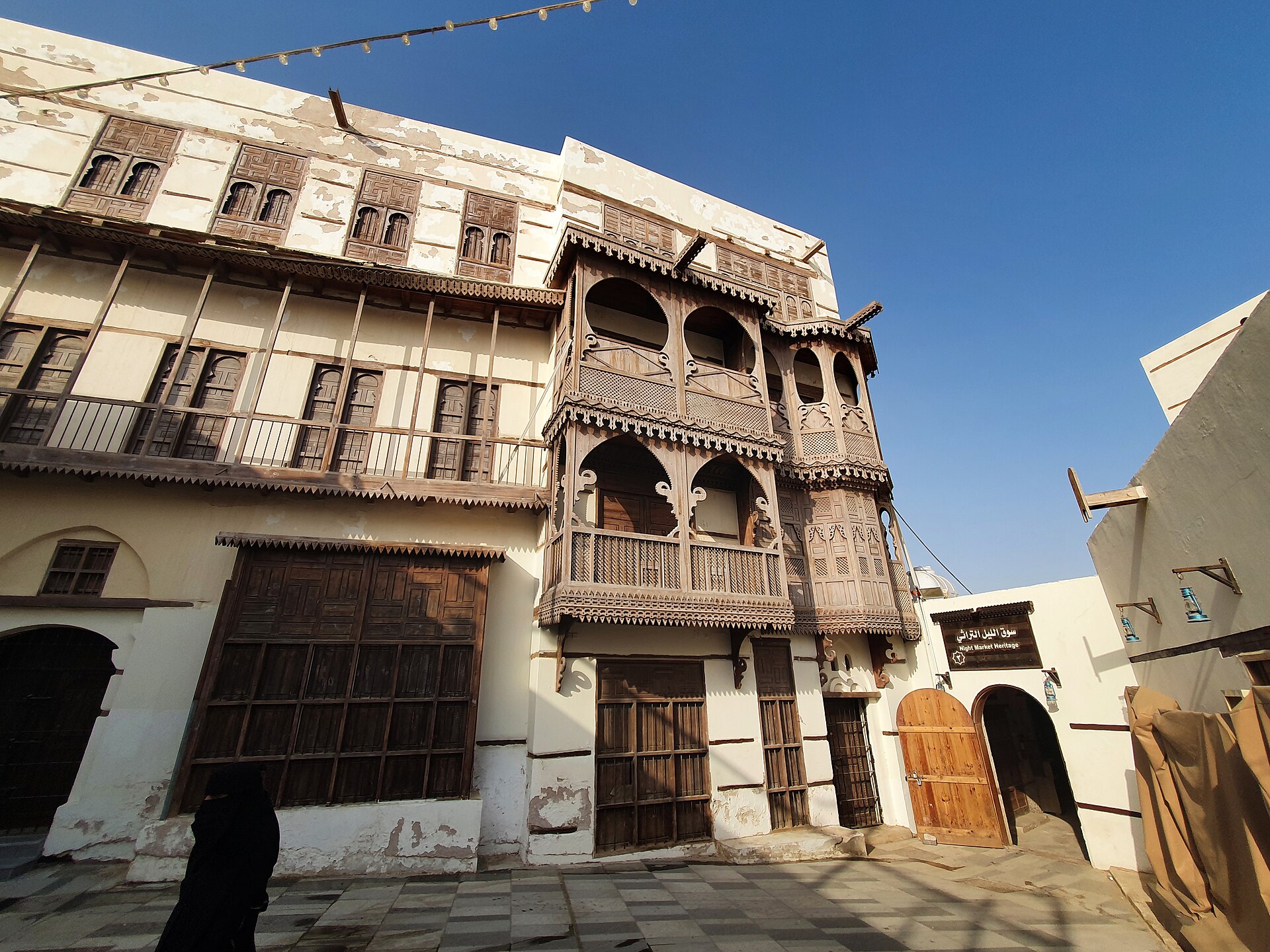 Traditional Hejazi architecture in old Yanbu showing coral-stone buildings with ornate wooden mashrabiyya balconies and carved doorways