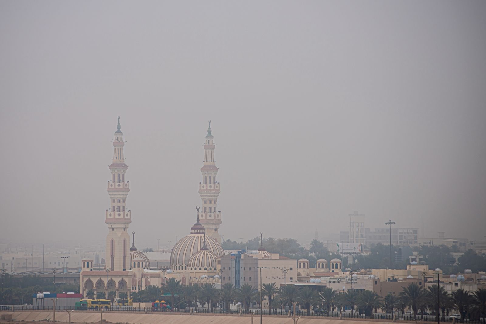 Arar city skyline showing a grand mosque with twin minarets and domed roof against a hazy desert sky