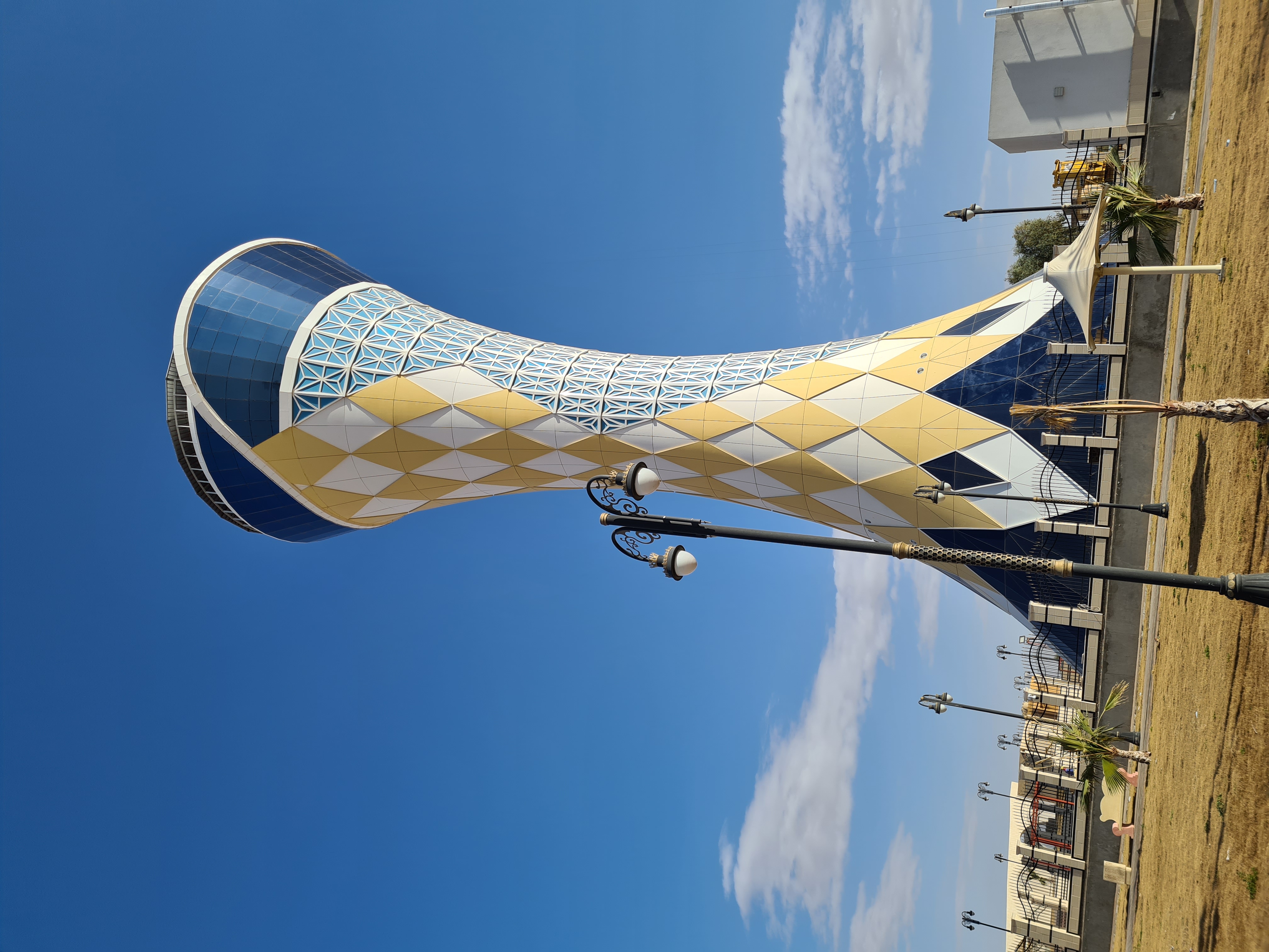 Arar Tower, a modern hourglass-shaped observation tower with gold and white geometric panels against a blue sky