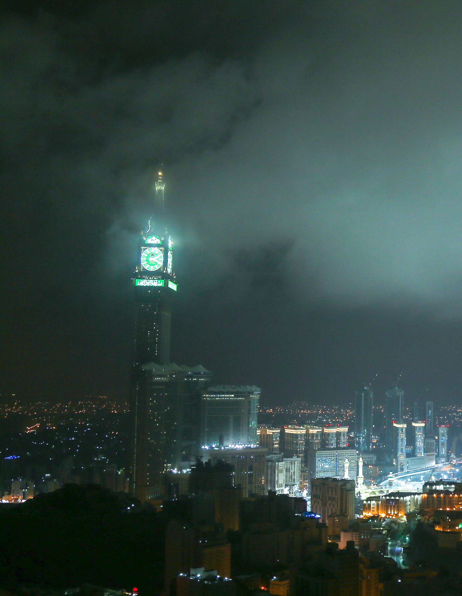 The Abraj al-Bait Clock Tower rising above Mecca's skyline at night with its green-lit face