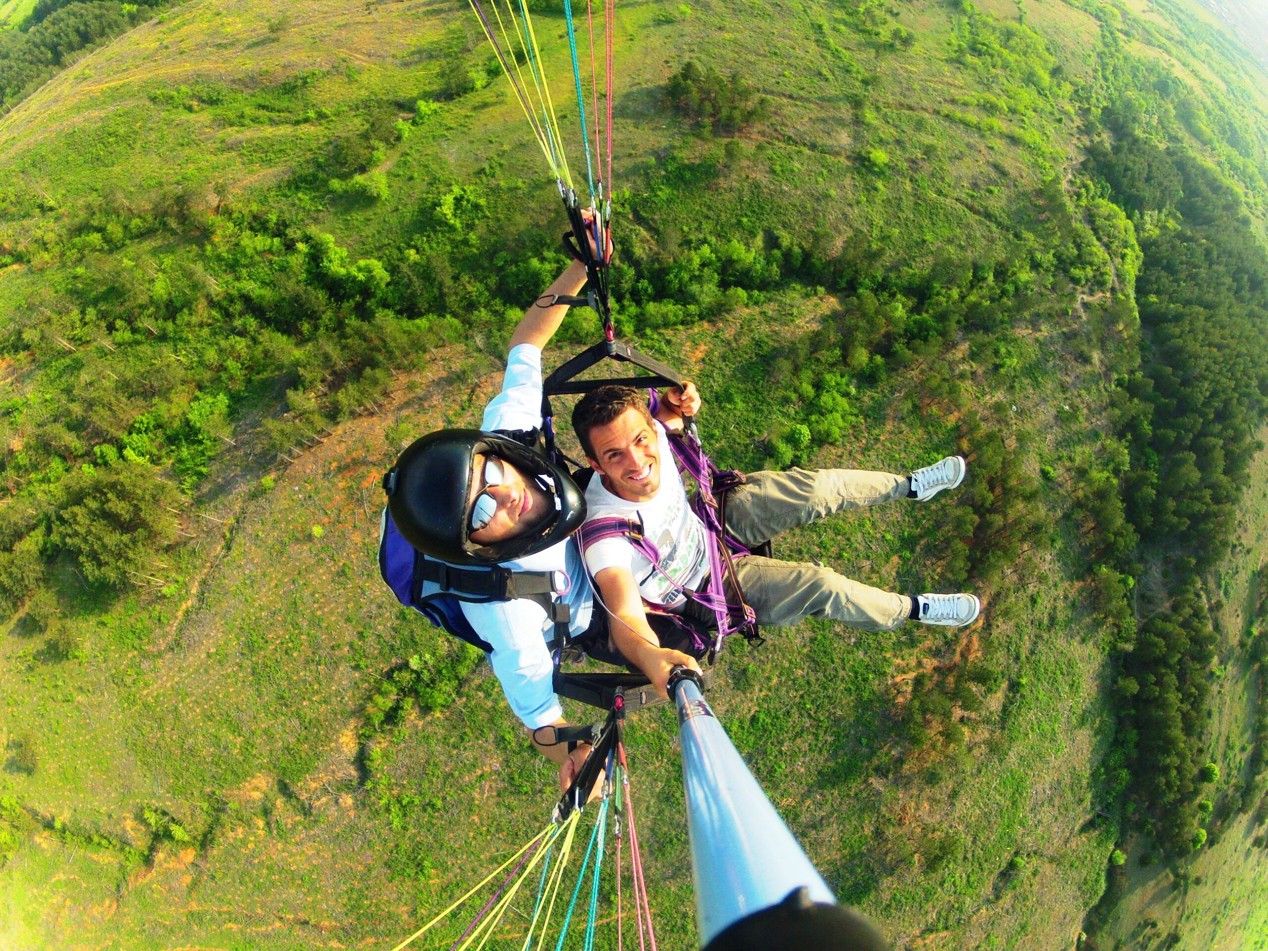 Tandem paragliding flight over mountain valley, similar to Abha highlands experience Saudi Arabia