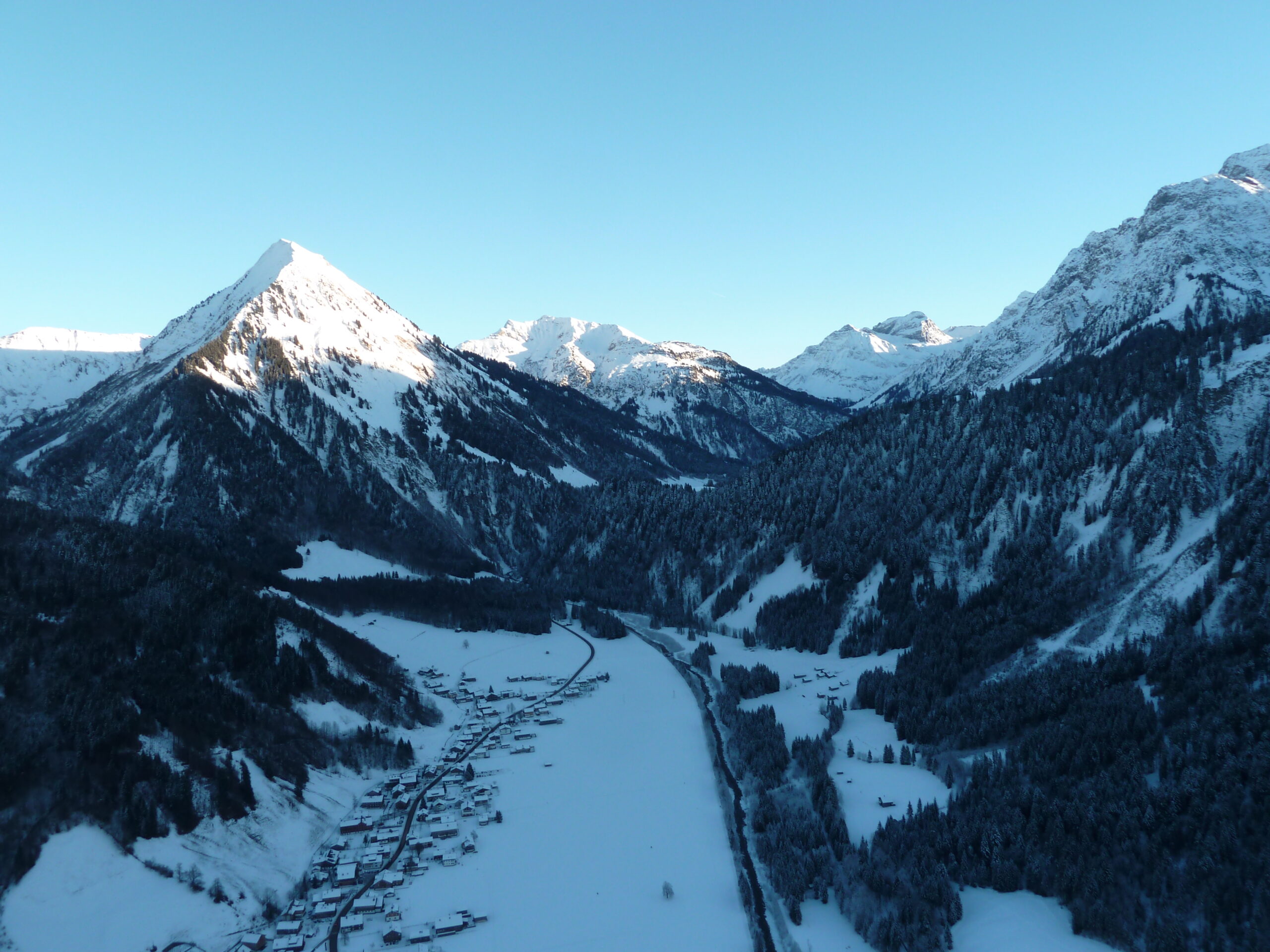 Paraglider soaring high above mountain highland terrain with valley views below