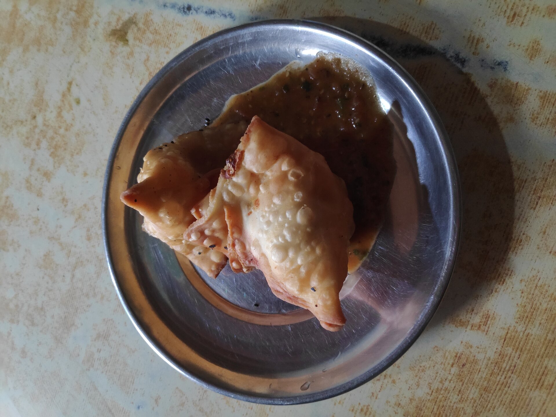 Crispy samboosa pastries served with green chutney on a plate