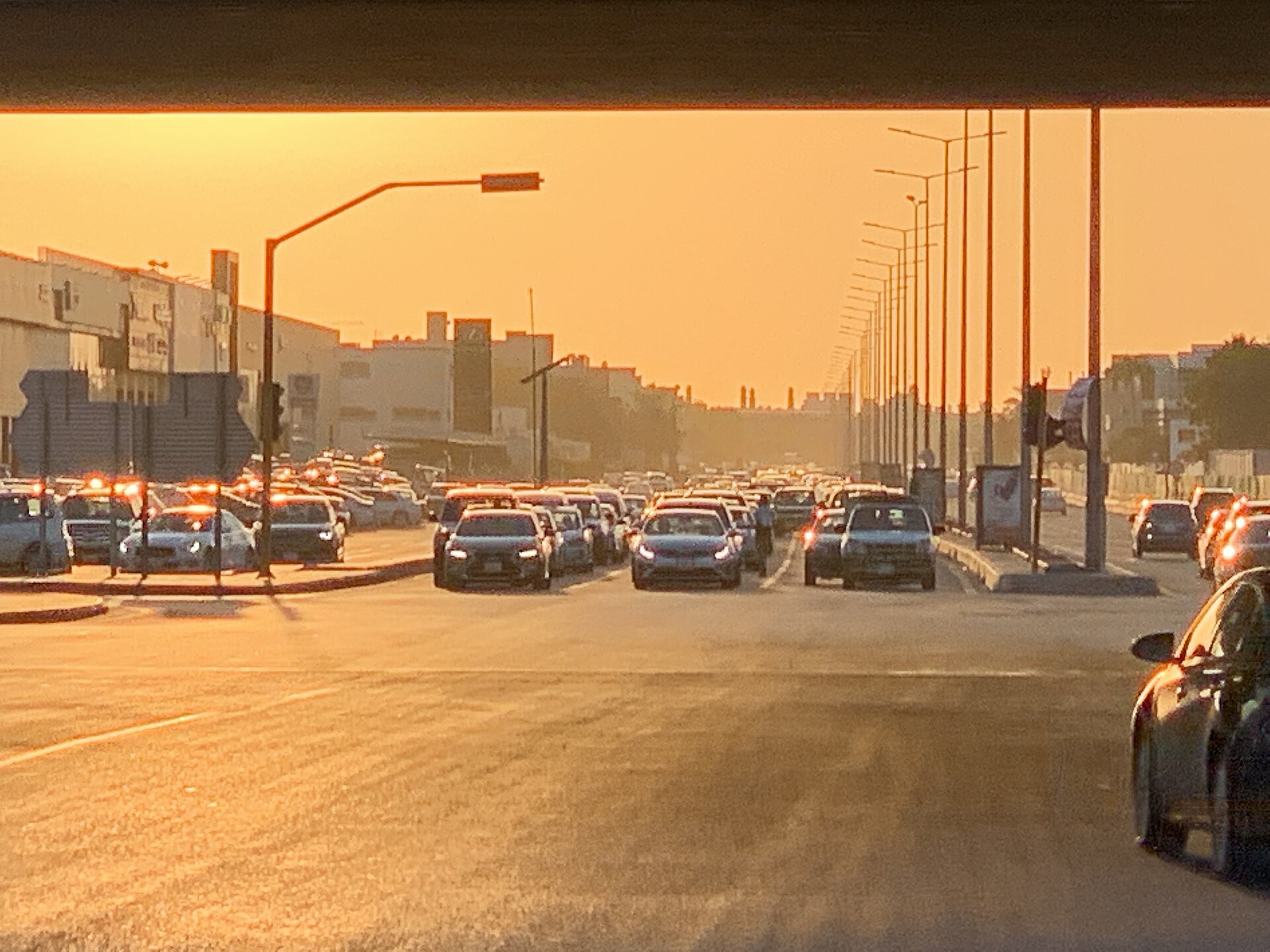Evening rush-hour traffic in Jeddah at sunset with cars queued at an intersection