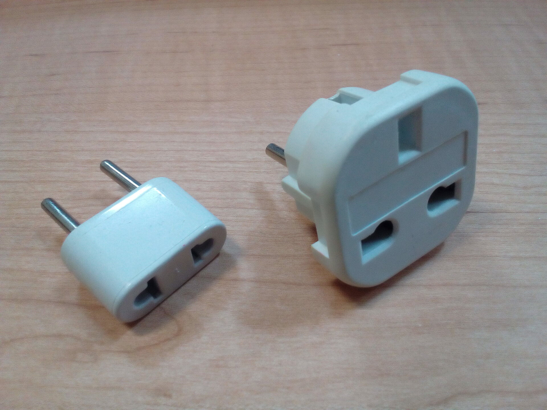 Two travel power adapters showing different plug type configurations for international travel