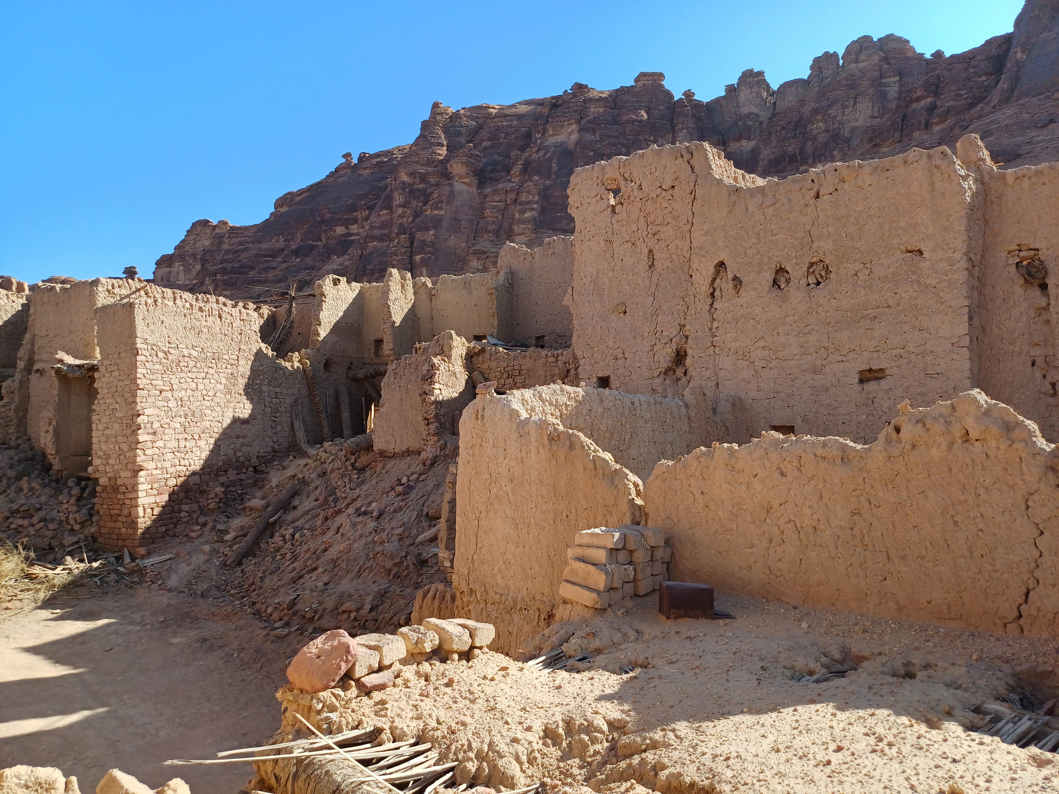 Historic mudbrick buildings of AlUla Old Town with sandstone cliffs rising behind them