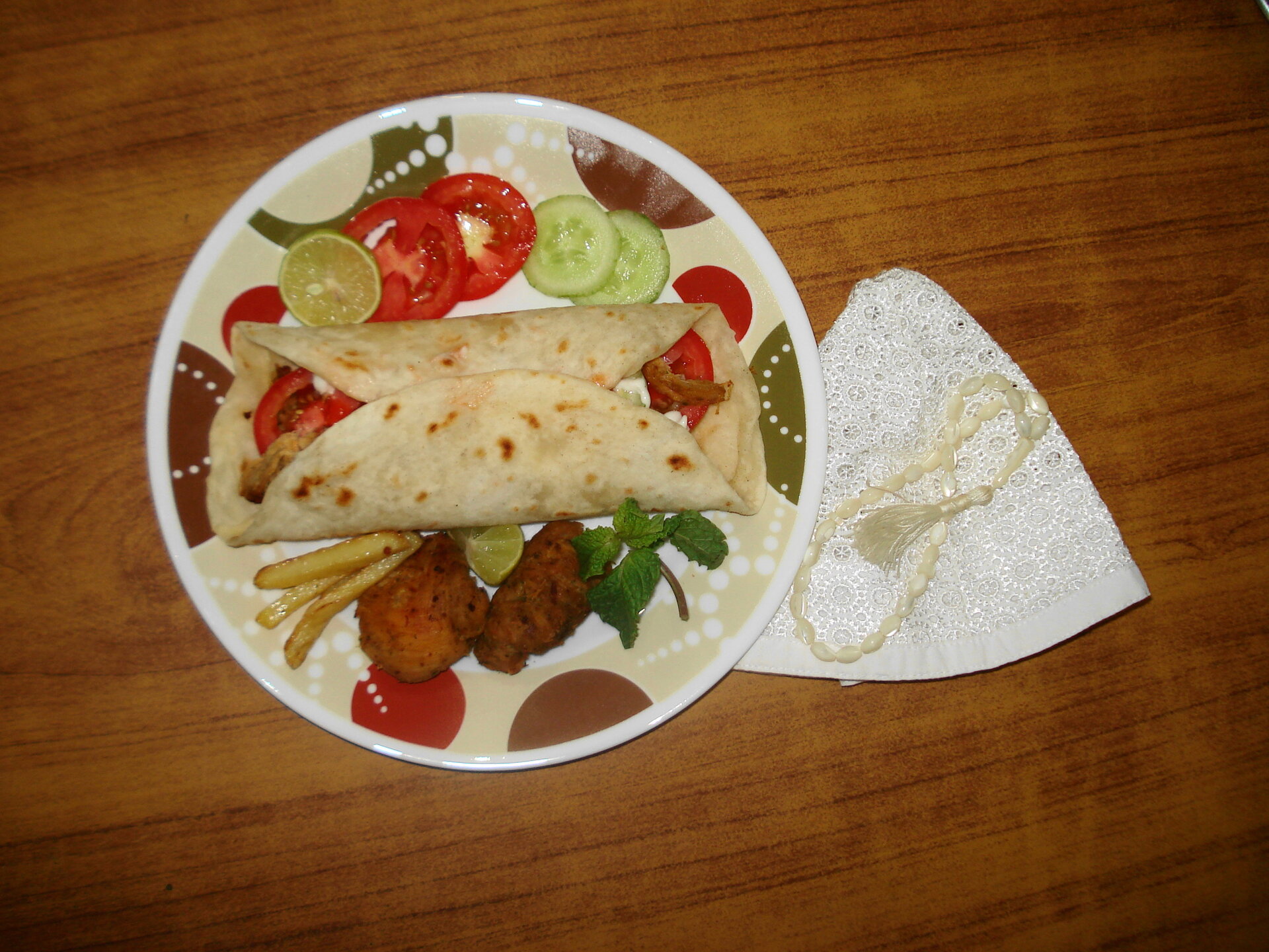 Saudi-style shawarma wrap with tomatoes, cucumbers and falafel on a plate