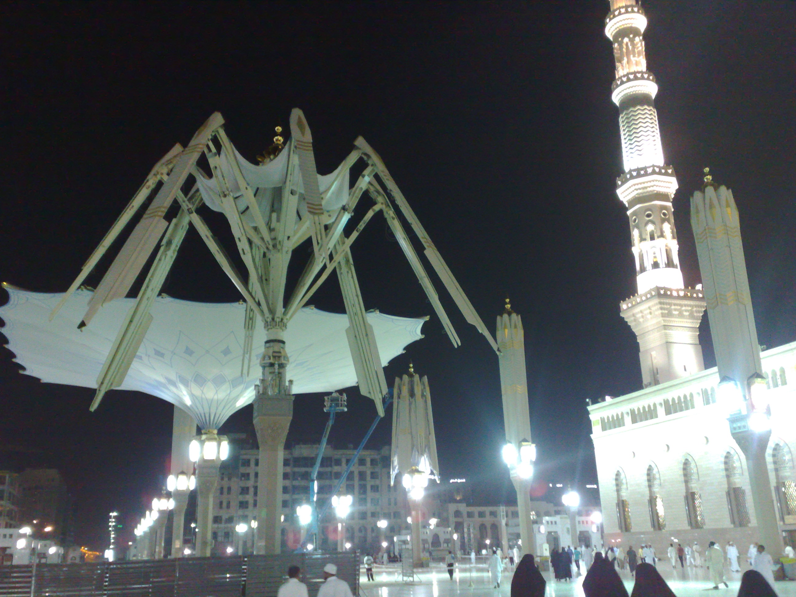 Masjid al-Nabawi courtyard at night with retractable umbrella structure and illuminated minaret