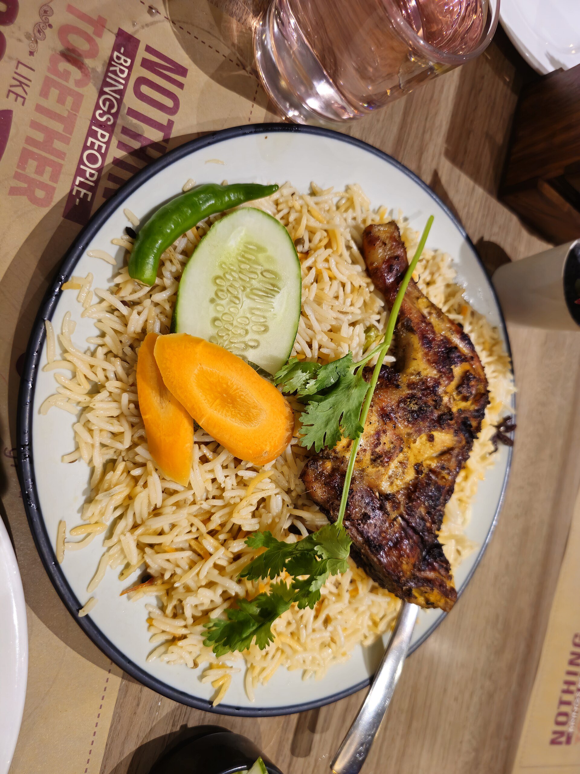 Individual chicken mandi plate with basmati rice, grilled chicken, cucumber and chilli at a modern Saudi restaurant