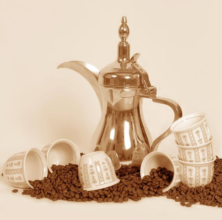 Traditional Saudi dallah coffee pot with handleless finjan cups and roasted coffee beans