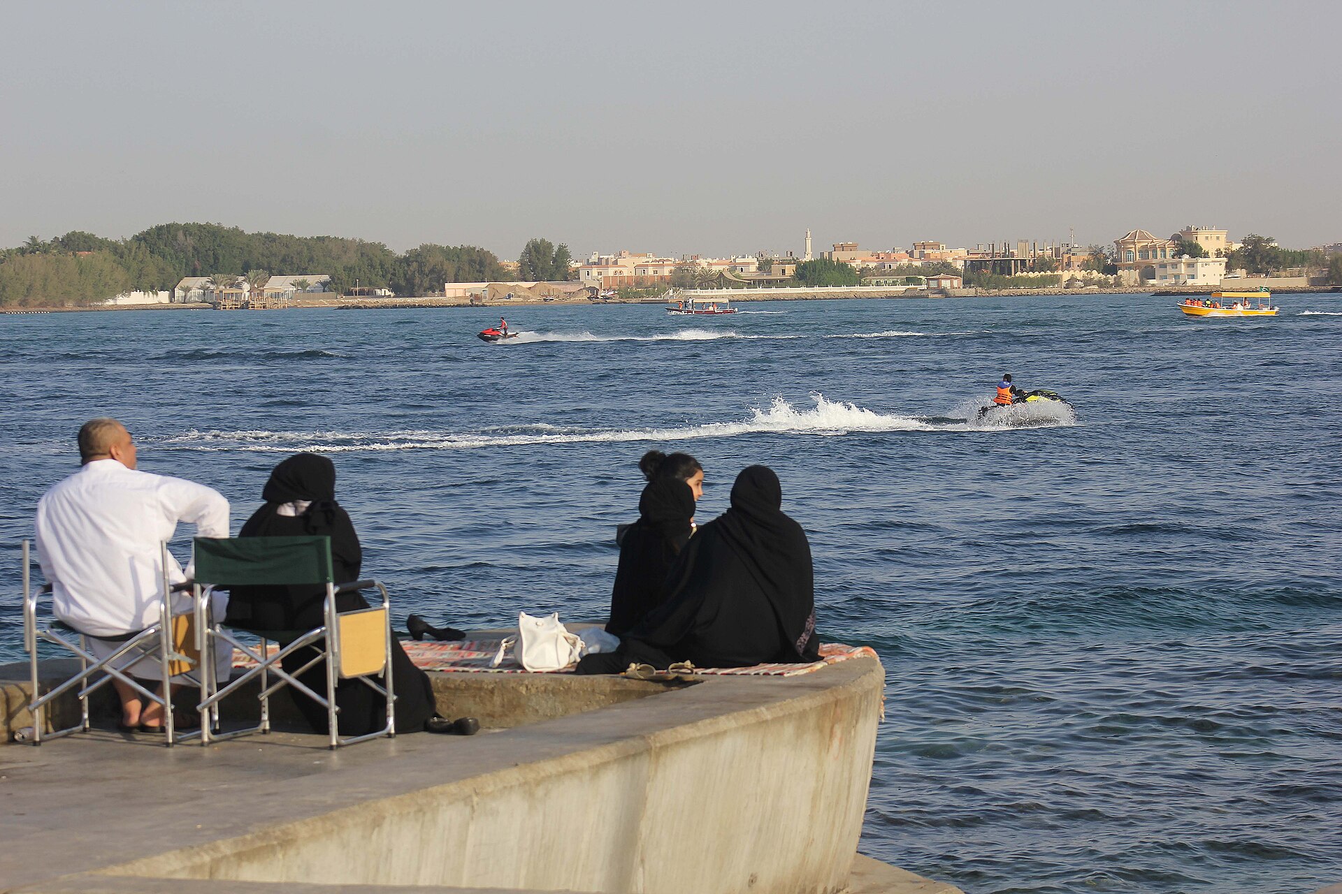 Saudi family enjoying the waterfront in Jeddah, watching jet skis on the Red Sea