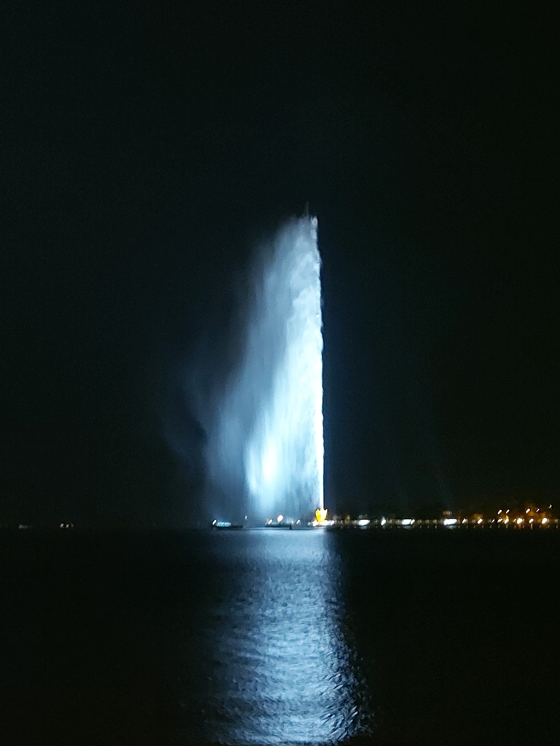 King Fahd Fountain illuminated at night in Jeddah, with the water jet glowing against the dark sky