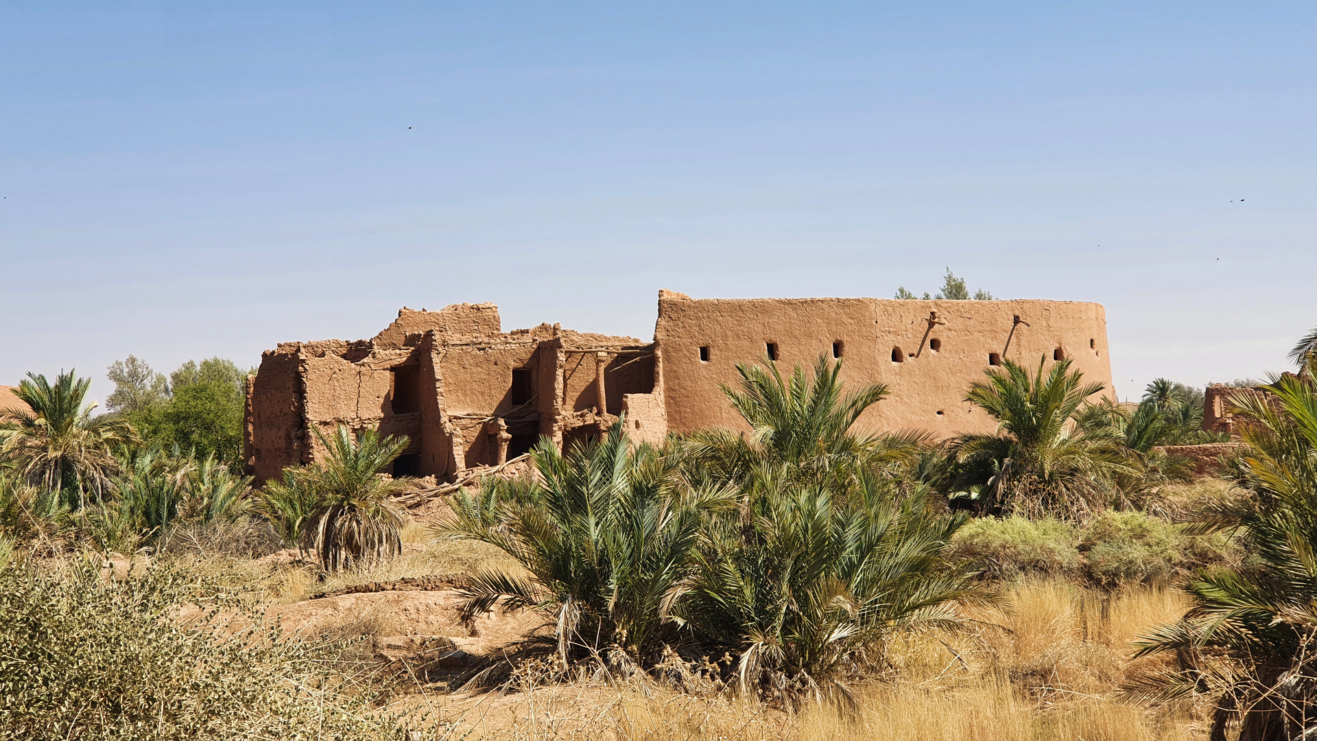 Yellow mud-brick houses with triangular windows and carved wooden doors at Ushaiger Heritage Village in the Najd region of Saudi Arabia
