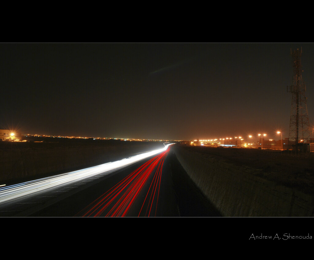 Night view of the Riyadh to Mecca highway with vehicle light trails stretching across the Saudi desert