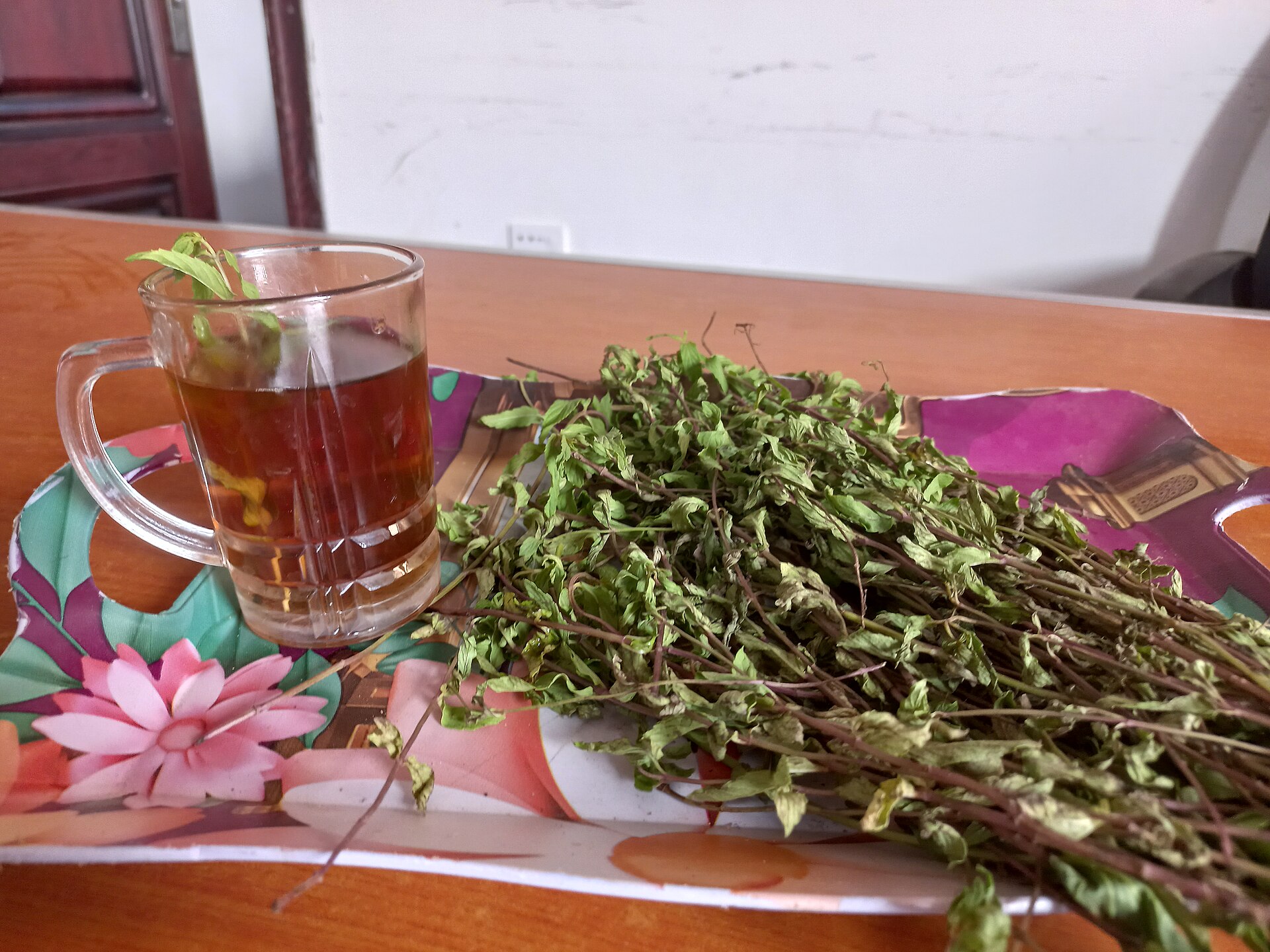 A glass cup of freshly brewed mint tea with fresh mint leaves