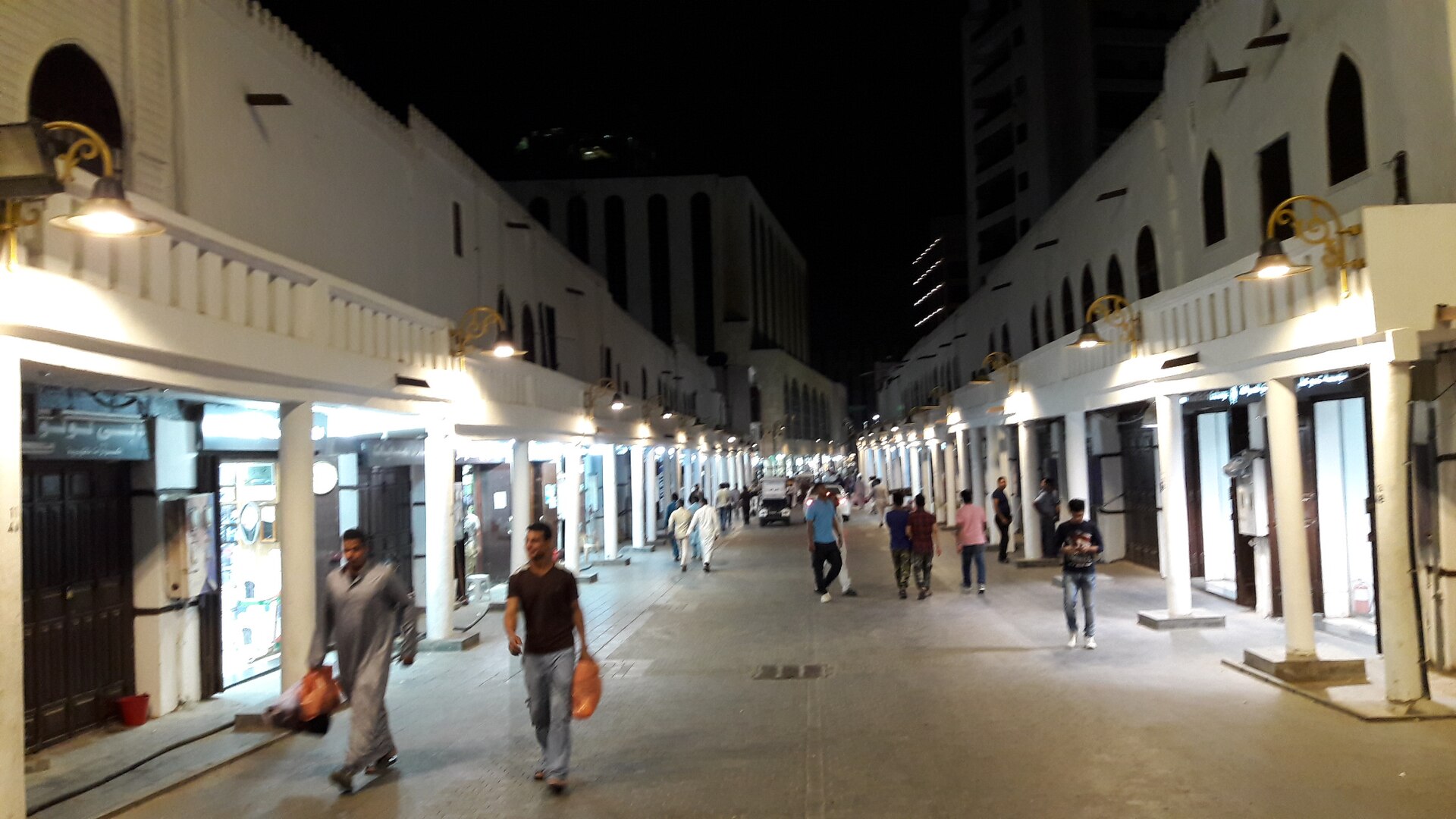 Qabil Street in old Jeddah at night, with pedestrians and traditional market stalls