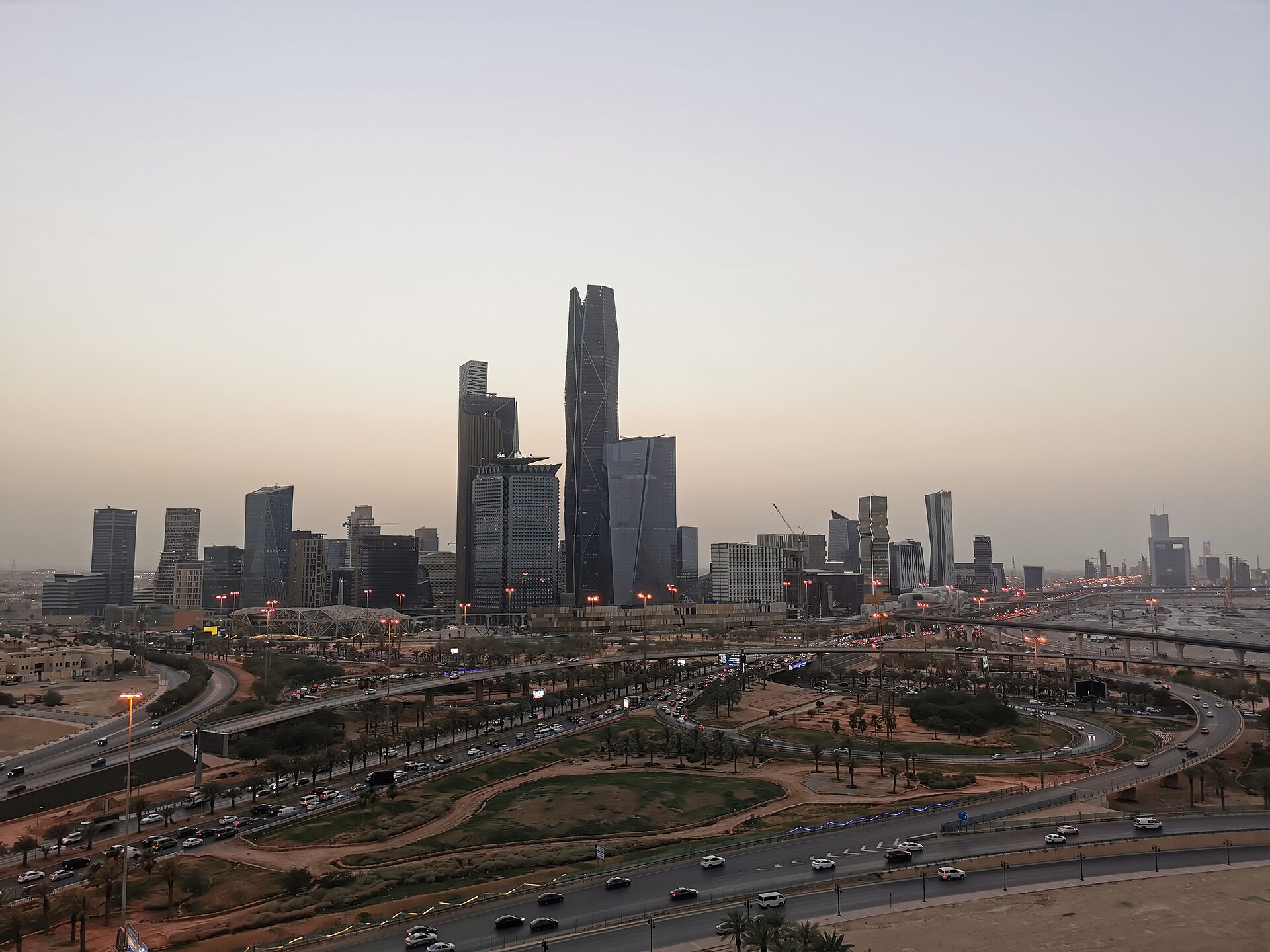 King Abdullah Financial District (KAFD) in Riyadh with modern skyscrapers and palm-lined highway at dusk