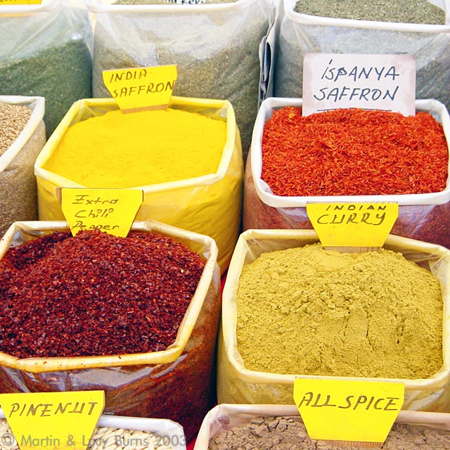 Saffron, allspice, curry, and other spices displayed in large bins at a traditional market