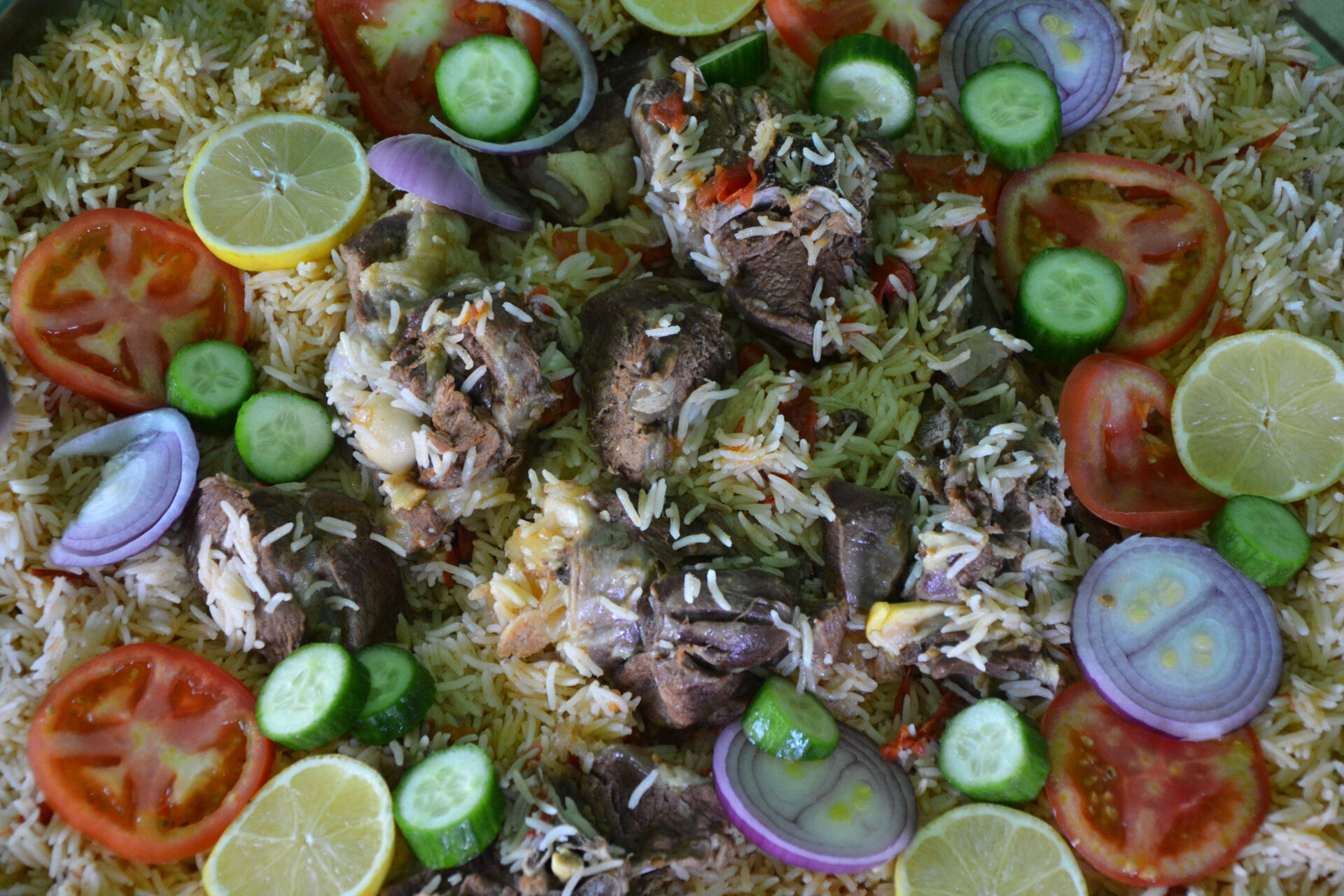 A traditional platter of kabsa, Saudi Arabia's national rice and meat dish, garnished with fresh vegetables