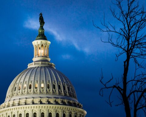 US Capitol dome illuminated at dusk against deep blue sky, Statue of Freedom atop the Tholos visible, symbolizing congressional war powers authority