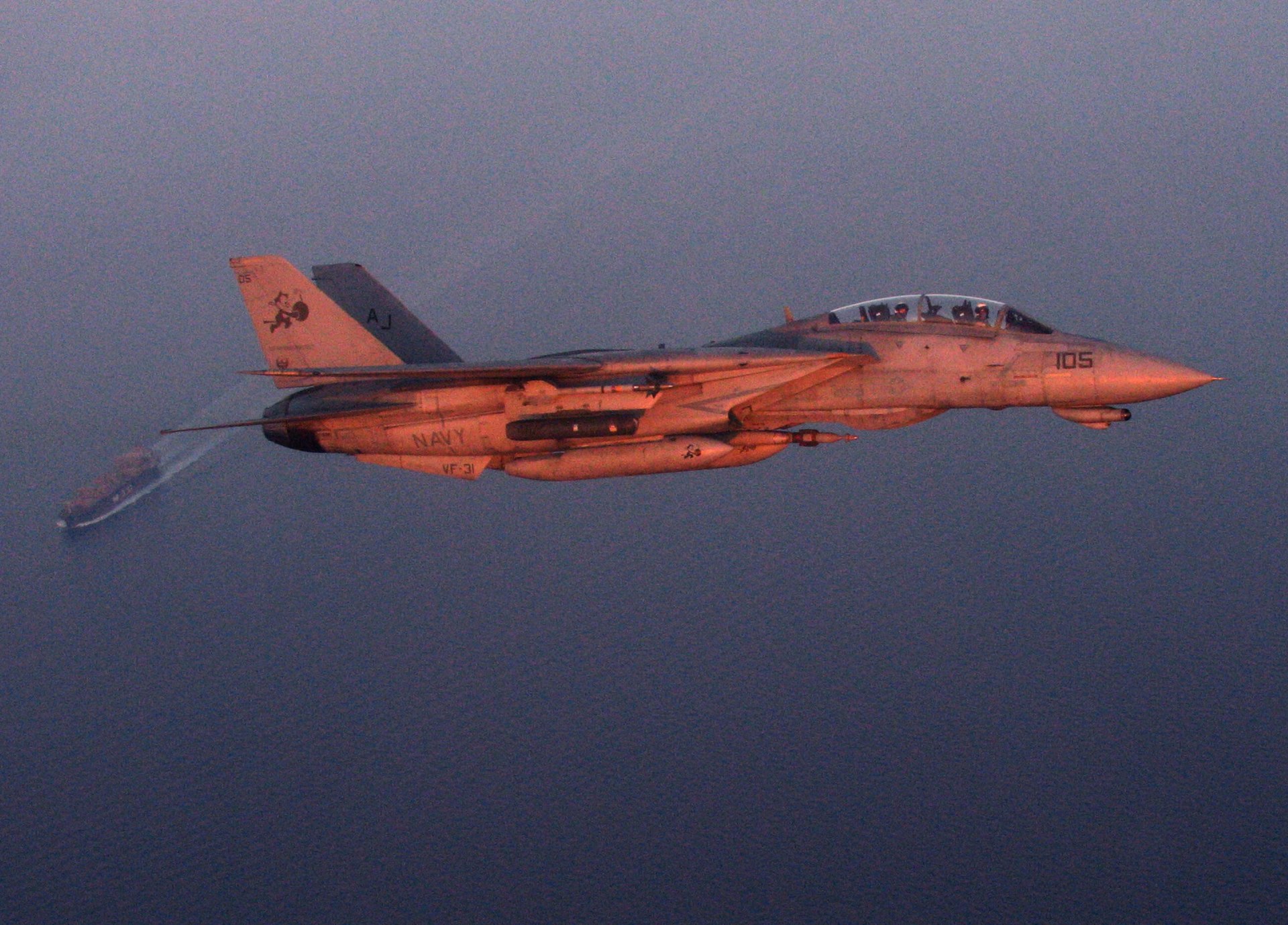 A US Navy F-14D Tomcat conducts a maritime security mission over an oil tanker in the Persian Gulf at sunset, 2005