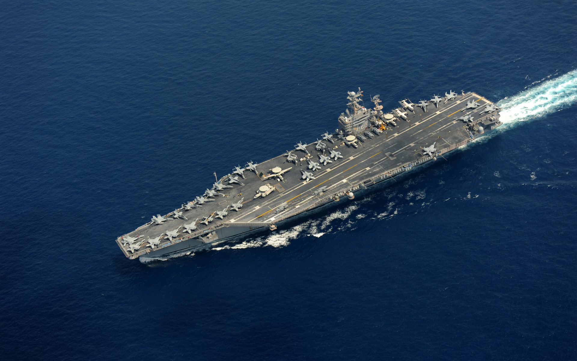 USS Abraham Lincoln (CVN-72) transiting the Indian Ocean with F/A-18 aircraft deployed across the flight deck, representing US carrier power projection in the CENTCOM area of responsibility