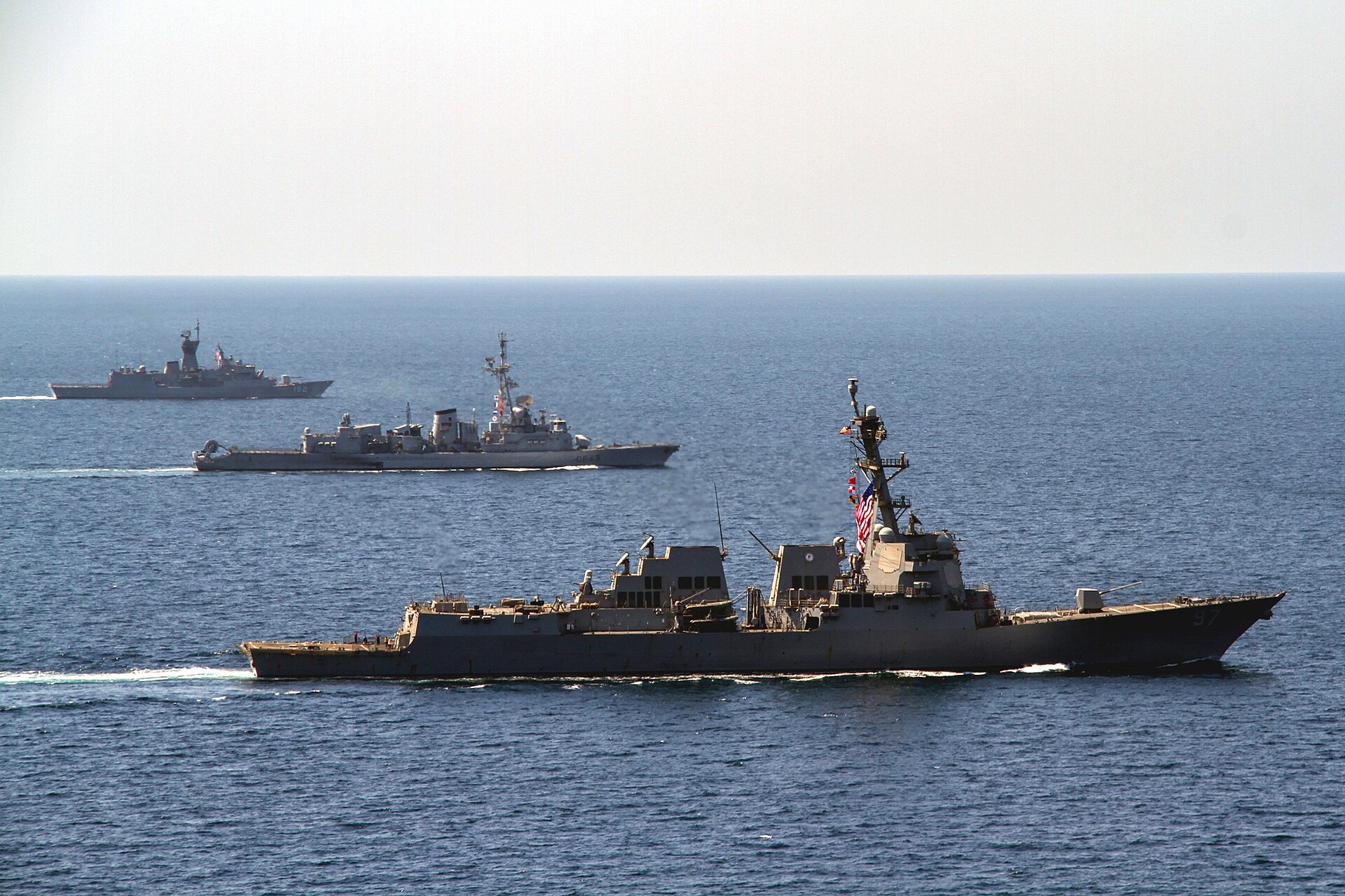 USS Halsey DDG-97 leads French frigate Jean de Vienne and Australian frigate HMAS Warrawunga in formation in the Arabian Gulf, March 2018 — the kind of multinational naval coalition absent from the April 2026 US blockade of Iranian ports
