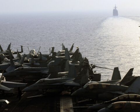 USS Nimitz carrier strike group transits the Strait of Hormuz with F/A-18 aircraft on deck and USS Princeton ahead, July 2007
