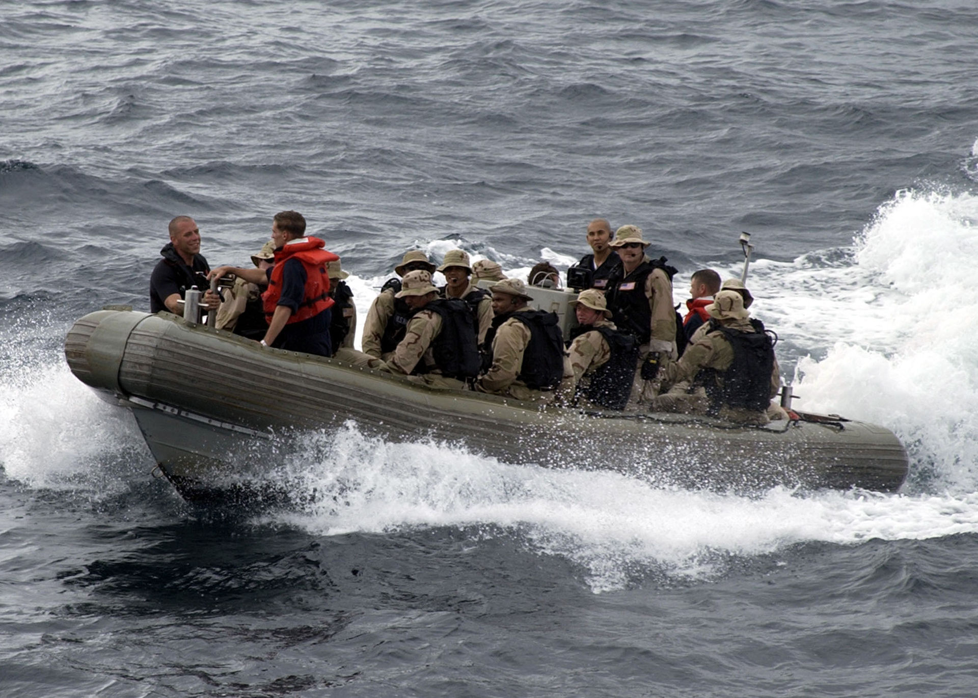 US Navy VBSS team in rigid-hull inflatable boat races toward merchant vessel for maritime interdiction boarding operation