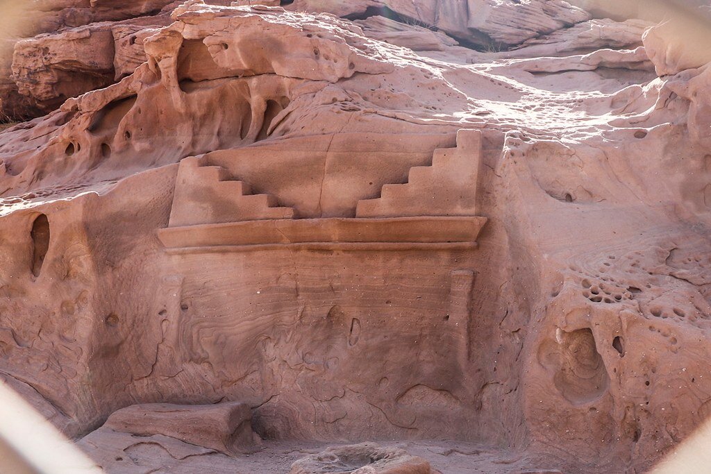 Nabataean tomb facade with stepped crowstep design carved into red sandstone cliff face at Wadi Disah Tabuk