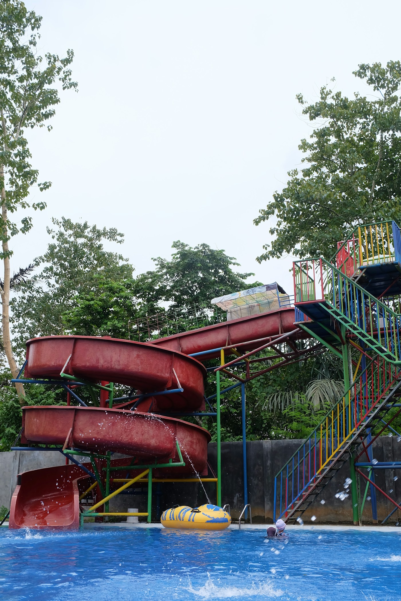 Red spiral water slides emptying into a splash pool at an outdoor water park