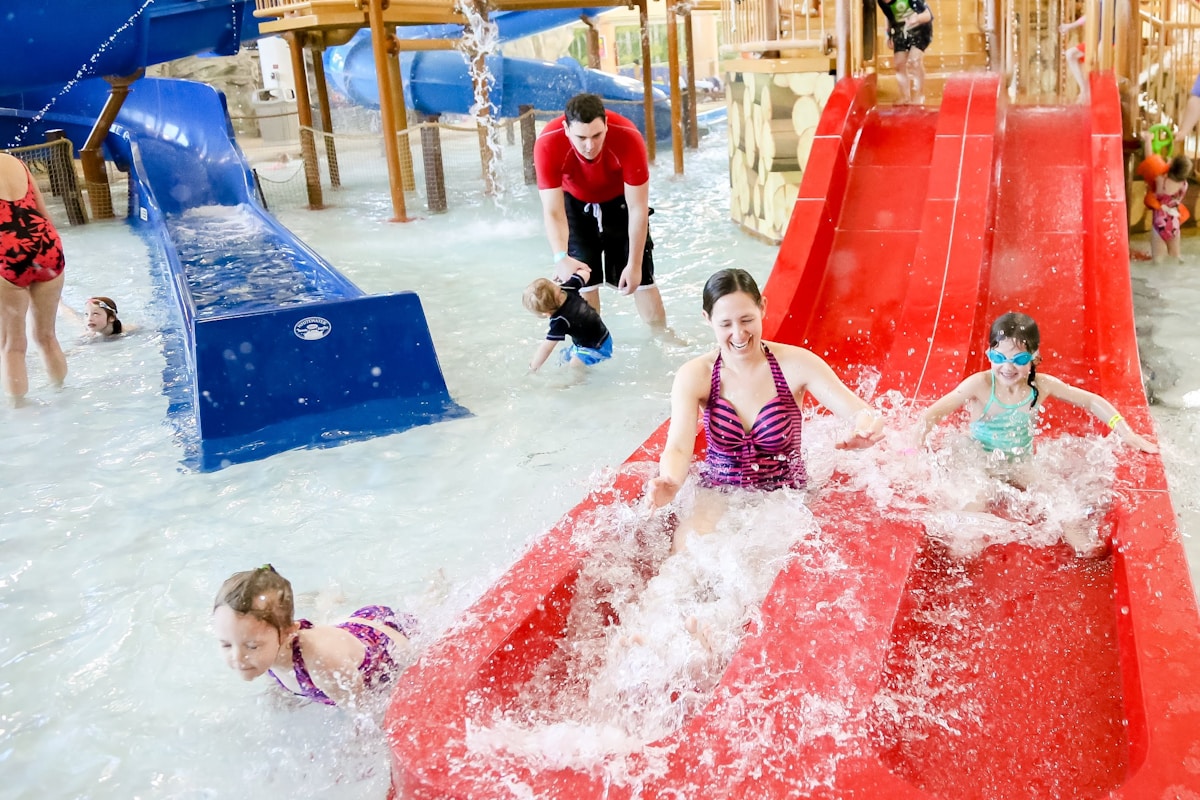 A family laughs together coming down red water slides at an indoor water park
