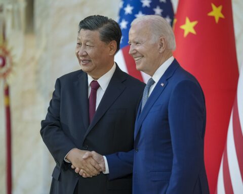 Xi Jinping and US President Biden shake hands at their bilateral meeting before the G20 Summit in Bali, November 2022, with the Chinese and American flags behind them