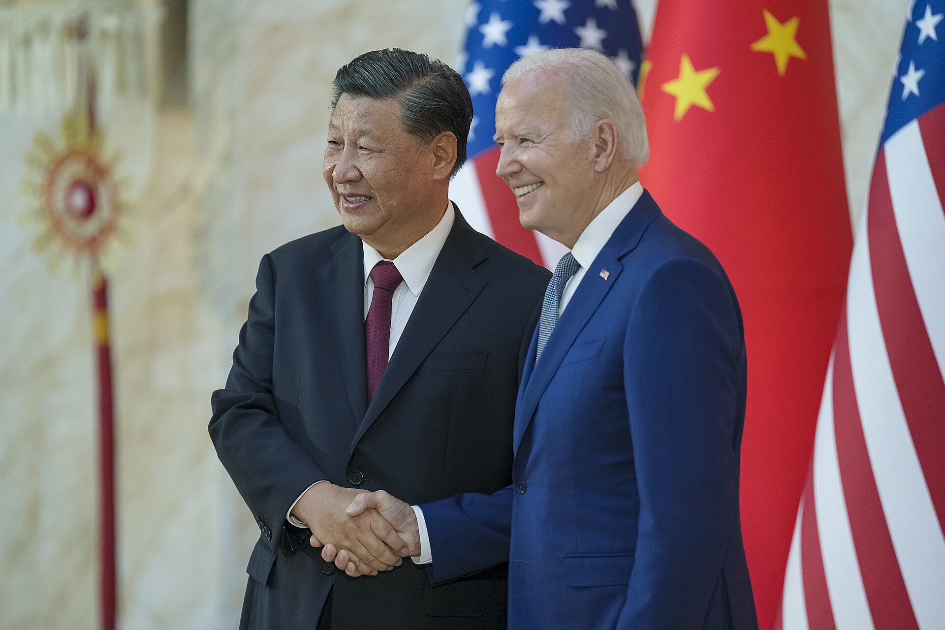 Xi Jinping and US President Biden shake hands at their bilateral meeting before the G20 Summit in Bali, November 2022, with the Chinese and American flags behind them