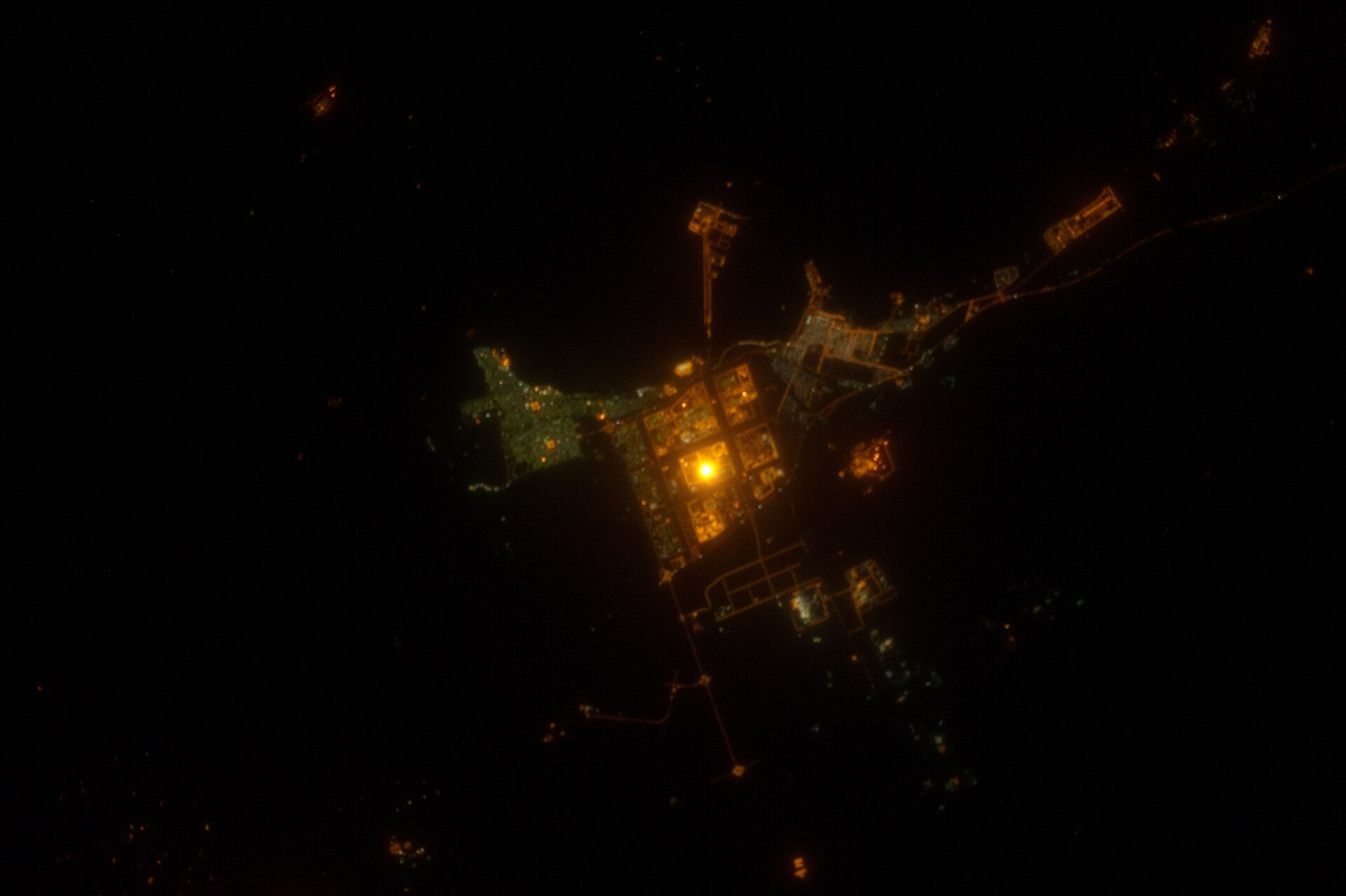 Saudi Arabia coastal industrial city at night photographed from the International Space Station, showing the illuminated grid of petrochemical facilities and infrastructure on the Gulf coast