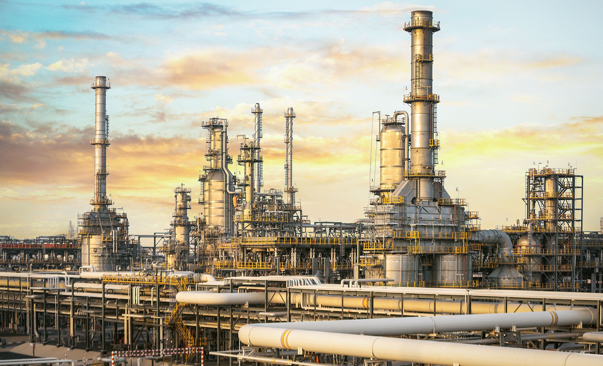 ADNOC Ruwais refinery complex in Abu Dhabi, UAE — sunset over petrochemical processing towers and pipelines