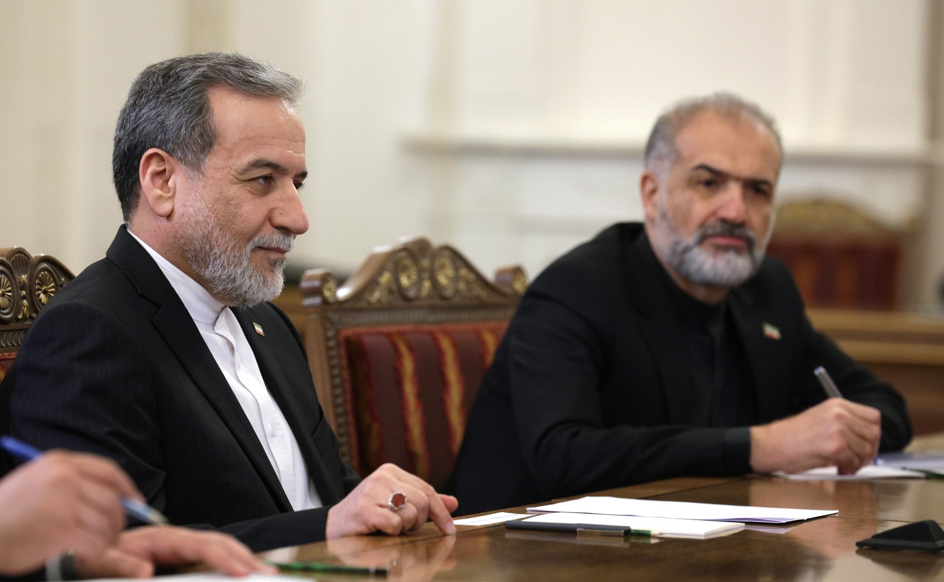 Iranian Foreign Minister Abbas Araghchi at a formal meeting table — Araghchi can report textual convergence because wording is within his mandate; binding commitment requires SNSC ratification by a body that includes IRGC Commander Vahidi