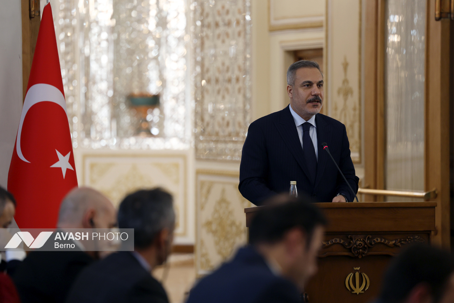 Turkish Foreign Minister Hakan Fidan addresses a press conference at the Iran Ministry of Foreign Affairs in Tehran, November 30 2025, with the Iranian state emblem visible on the podium