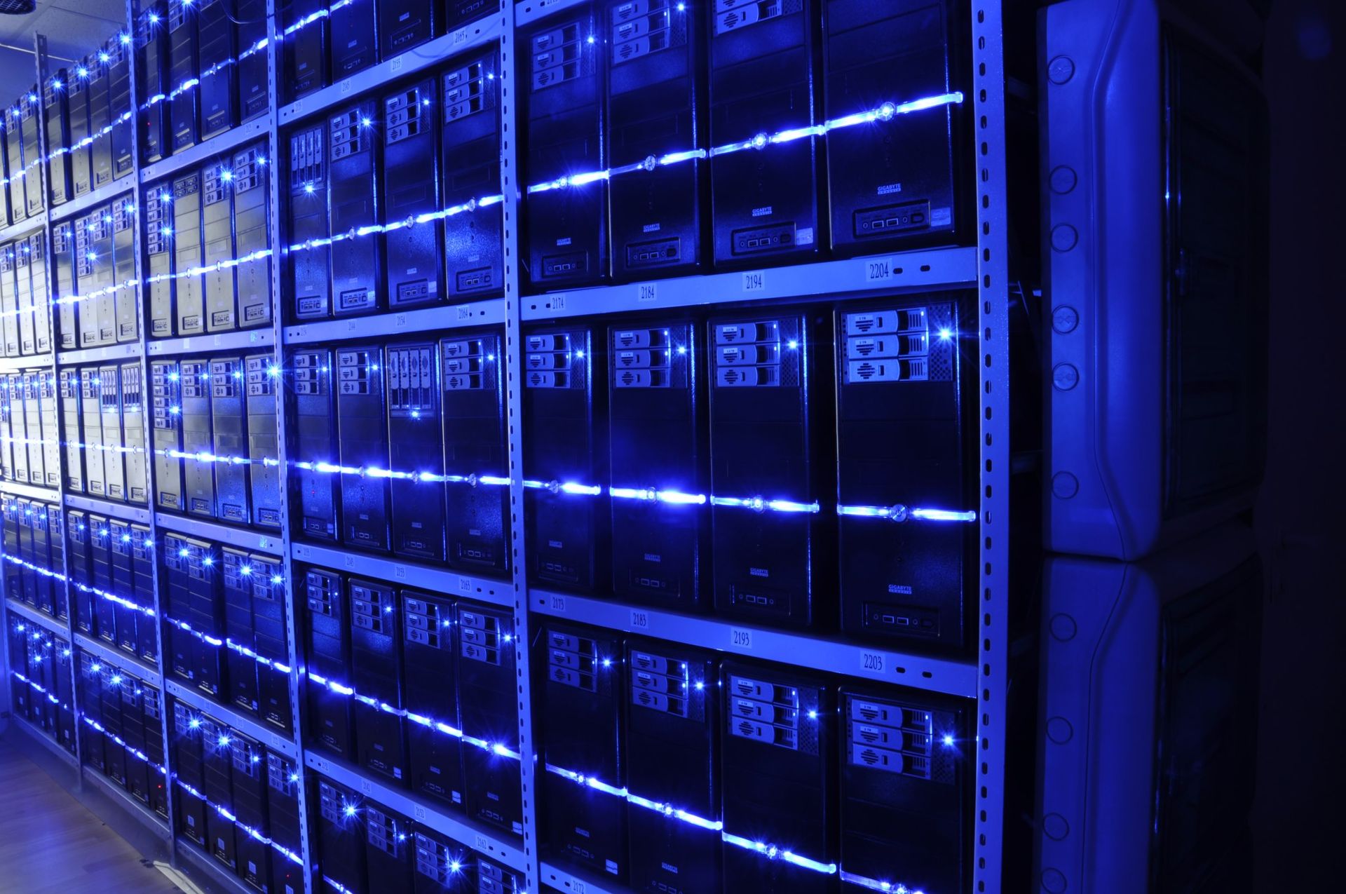 Server racks with blue LED indicators inside a data centre facility, representing AI computing infrastructure