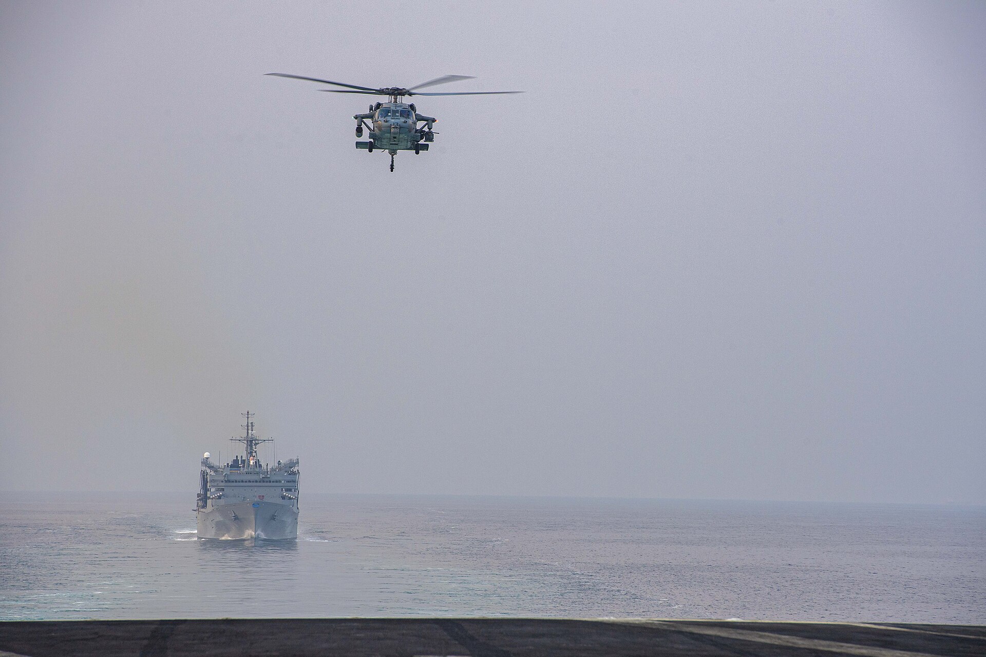 Eisenhower Carrier Strike Group ships and helicopter transit Strait of Hormuz during naval operation